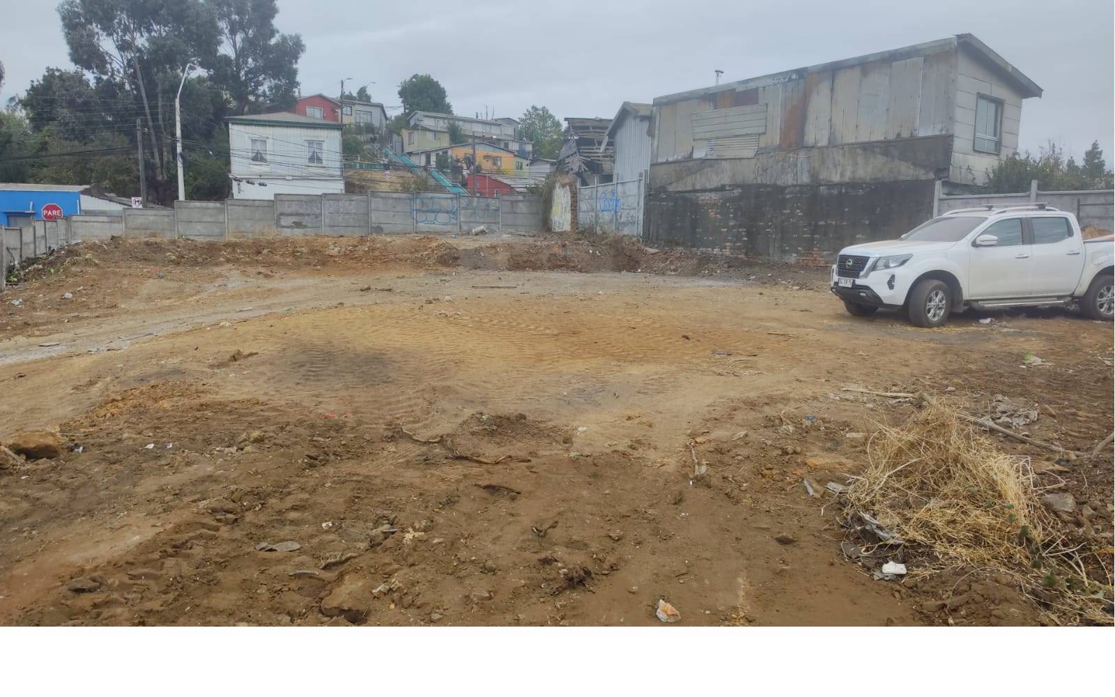 Superficie de tierra con camioneta blanca estacionada al costado