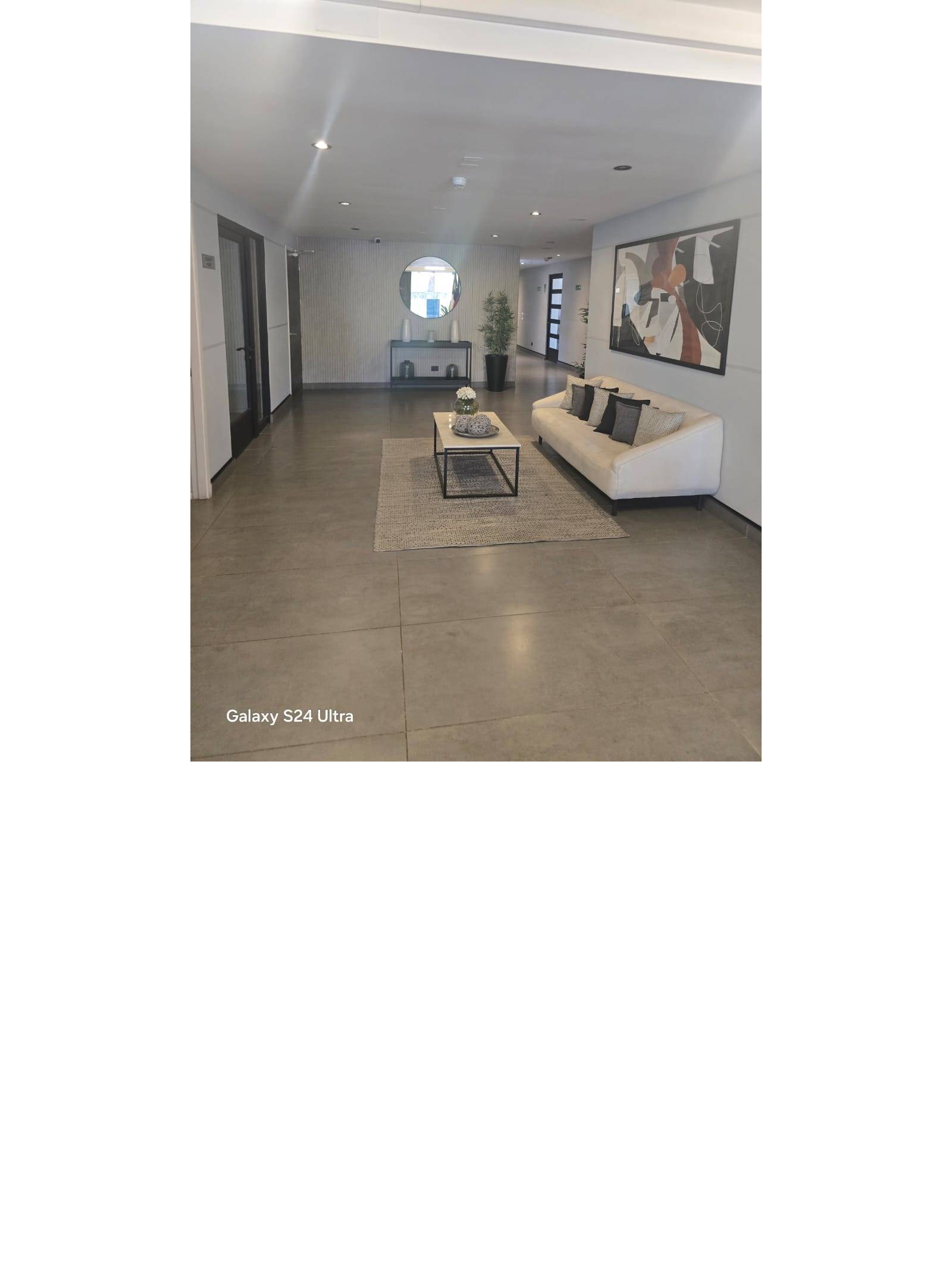 Hall de acceso con sala de espera amoblada y decoración moderna.