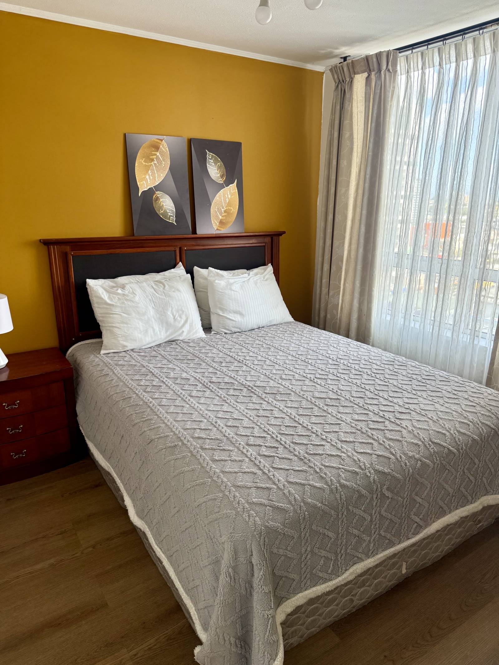 Dormitorio principal con cama de dos plazas y ventana con cortinas.