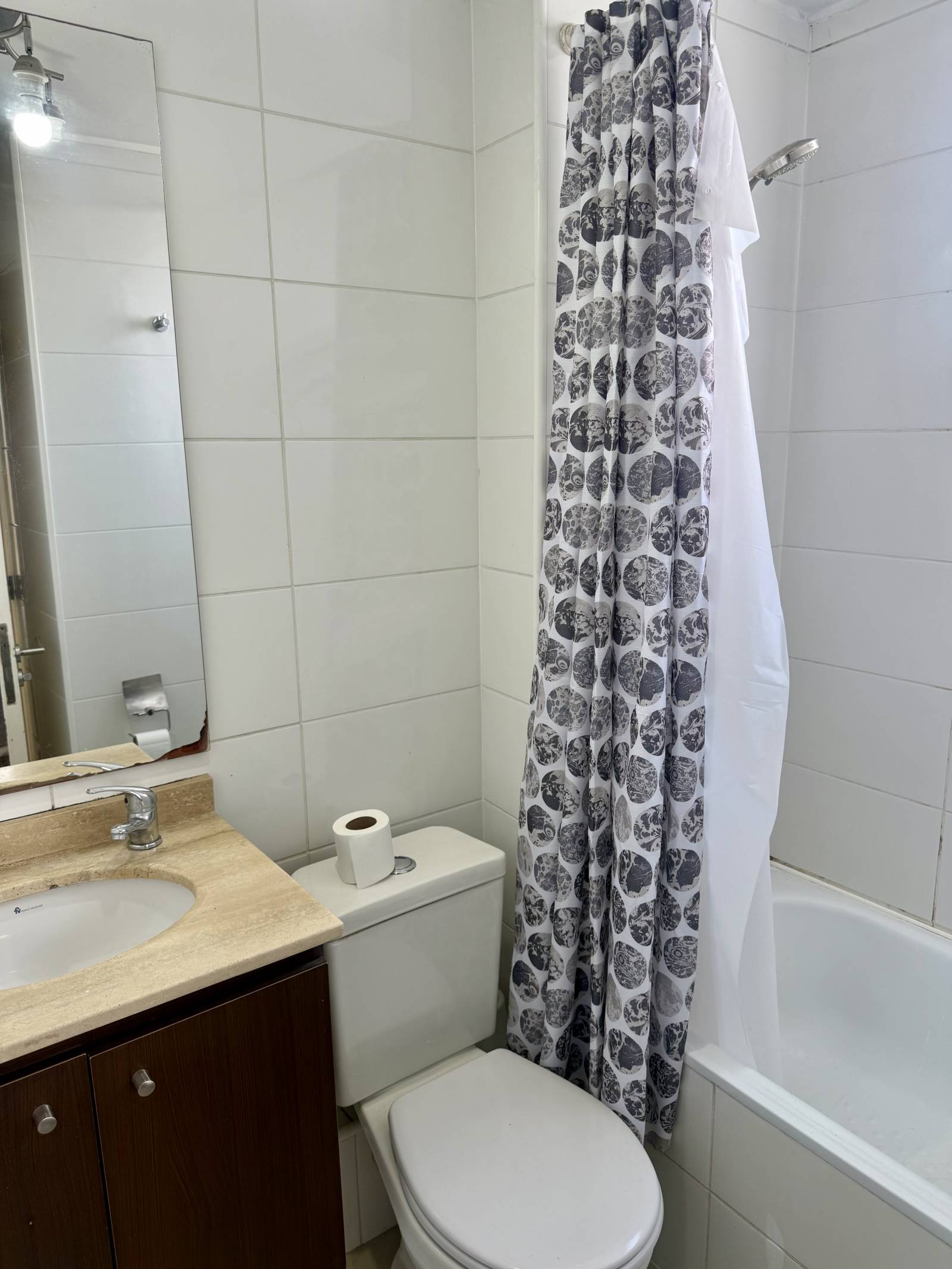 Baño completo con vanitorio, inodoro y tina con cortina.