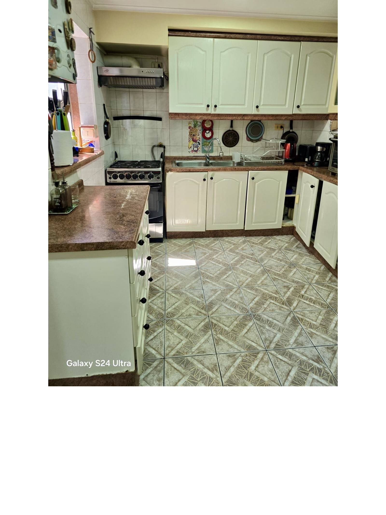 Cocina equipada con muebles blancos y encimera marrón