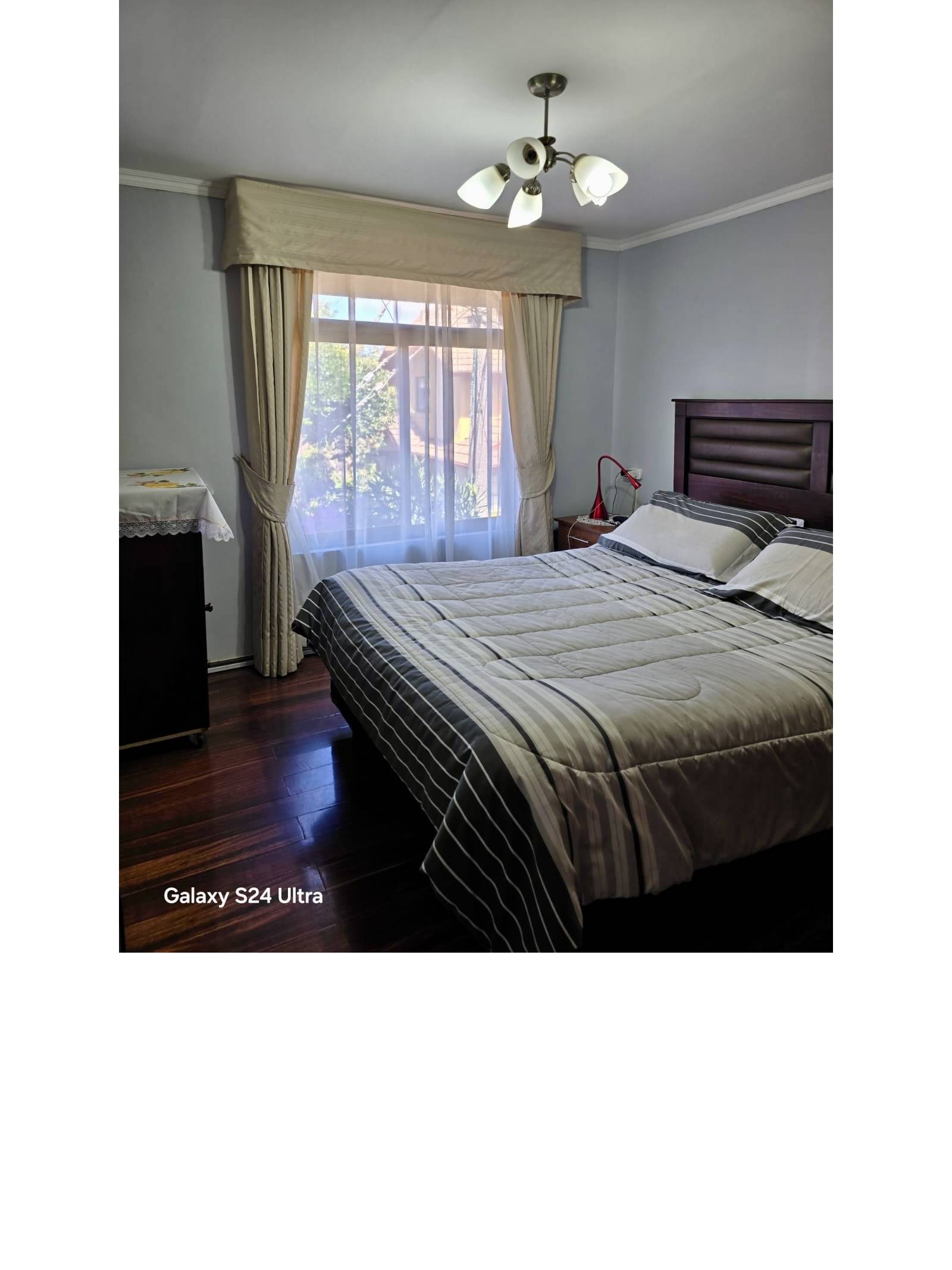 Dormitorio principal con cama matrimonial y ventana luminosa
