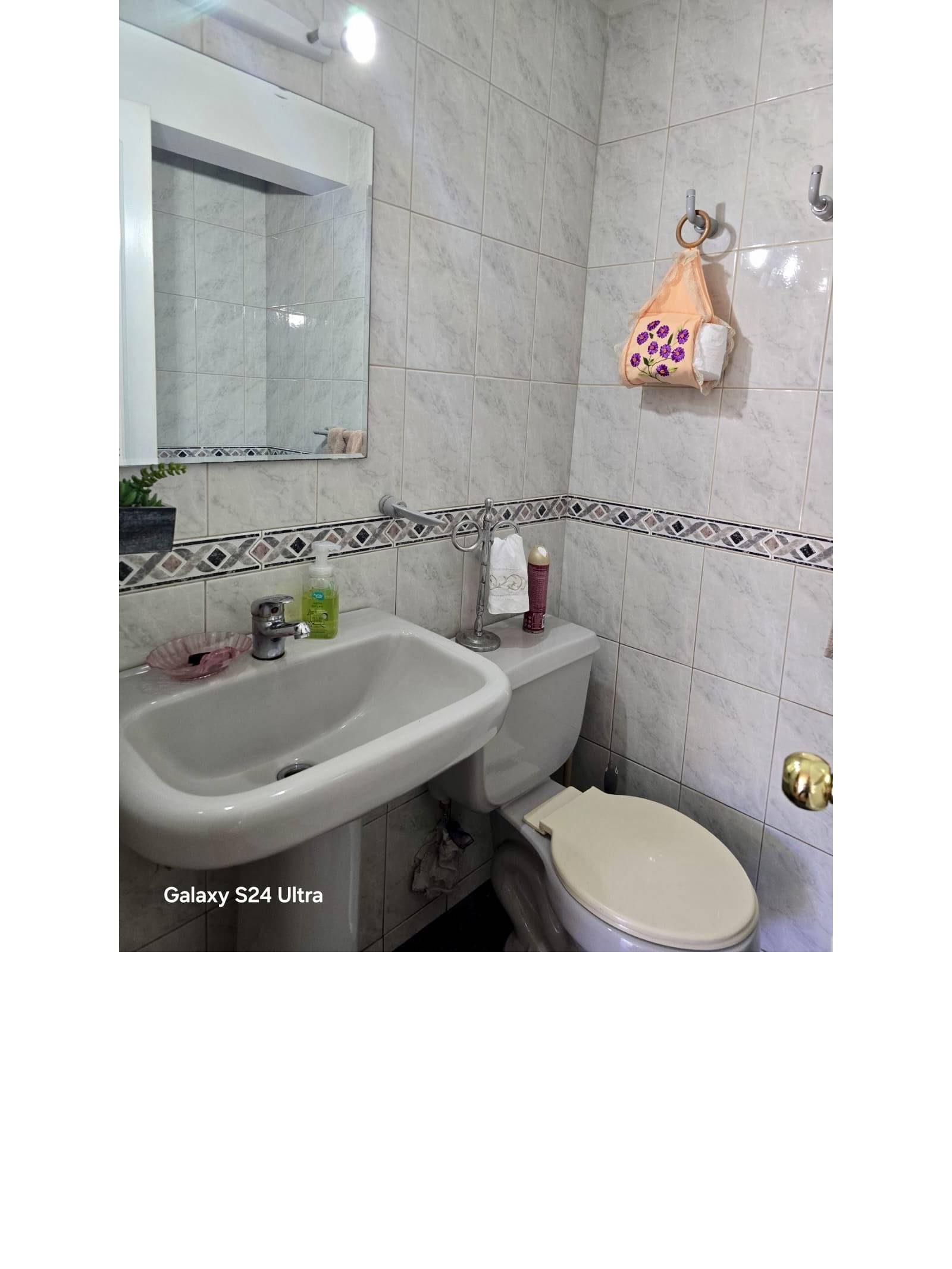 Baño con lavamanos blanco, sanitario y muros cerámicos