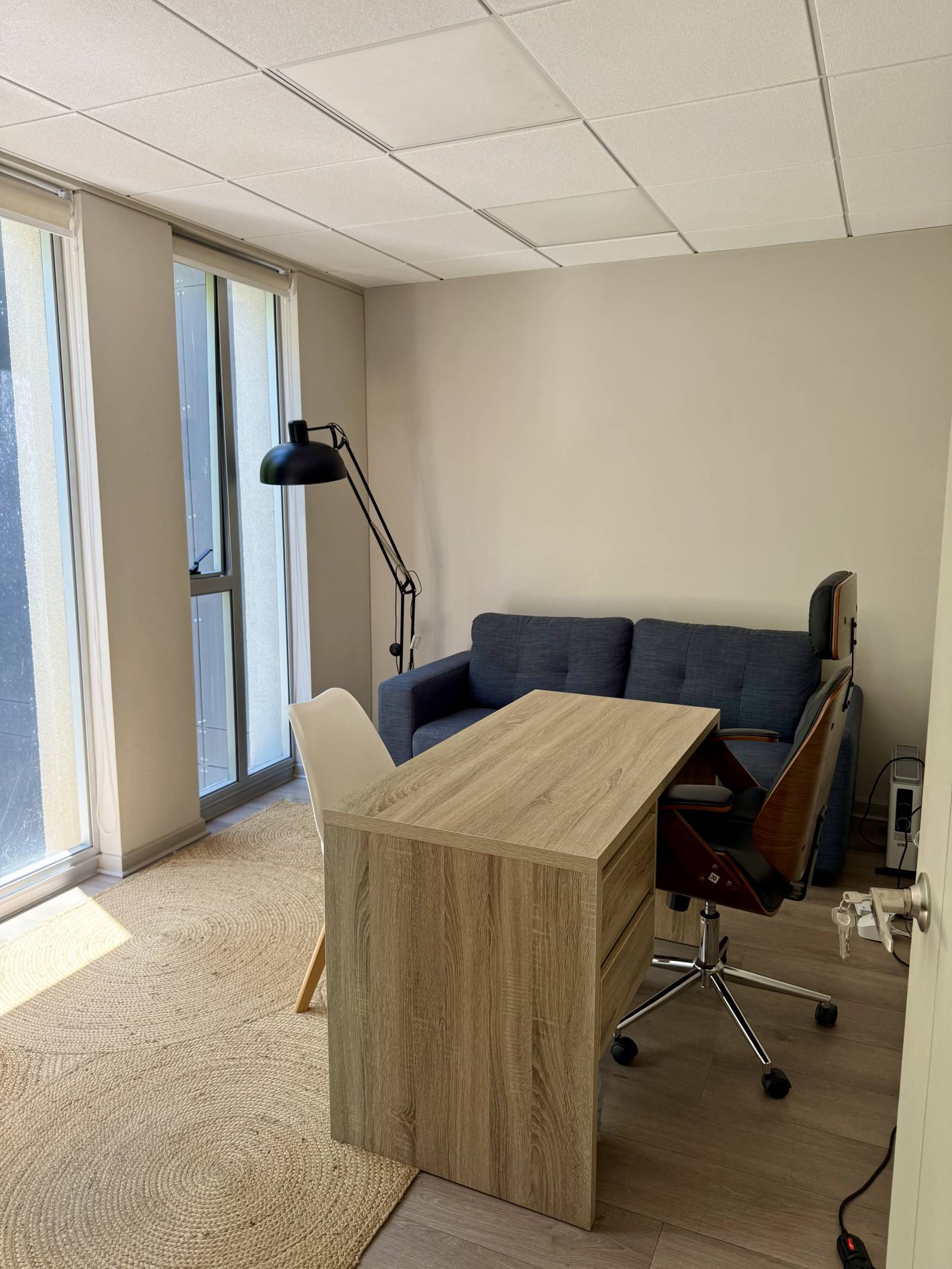 Privado u oficina con escritorio, sillón y ventanal luminoso.