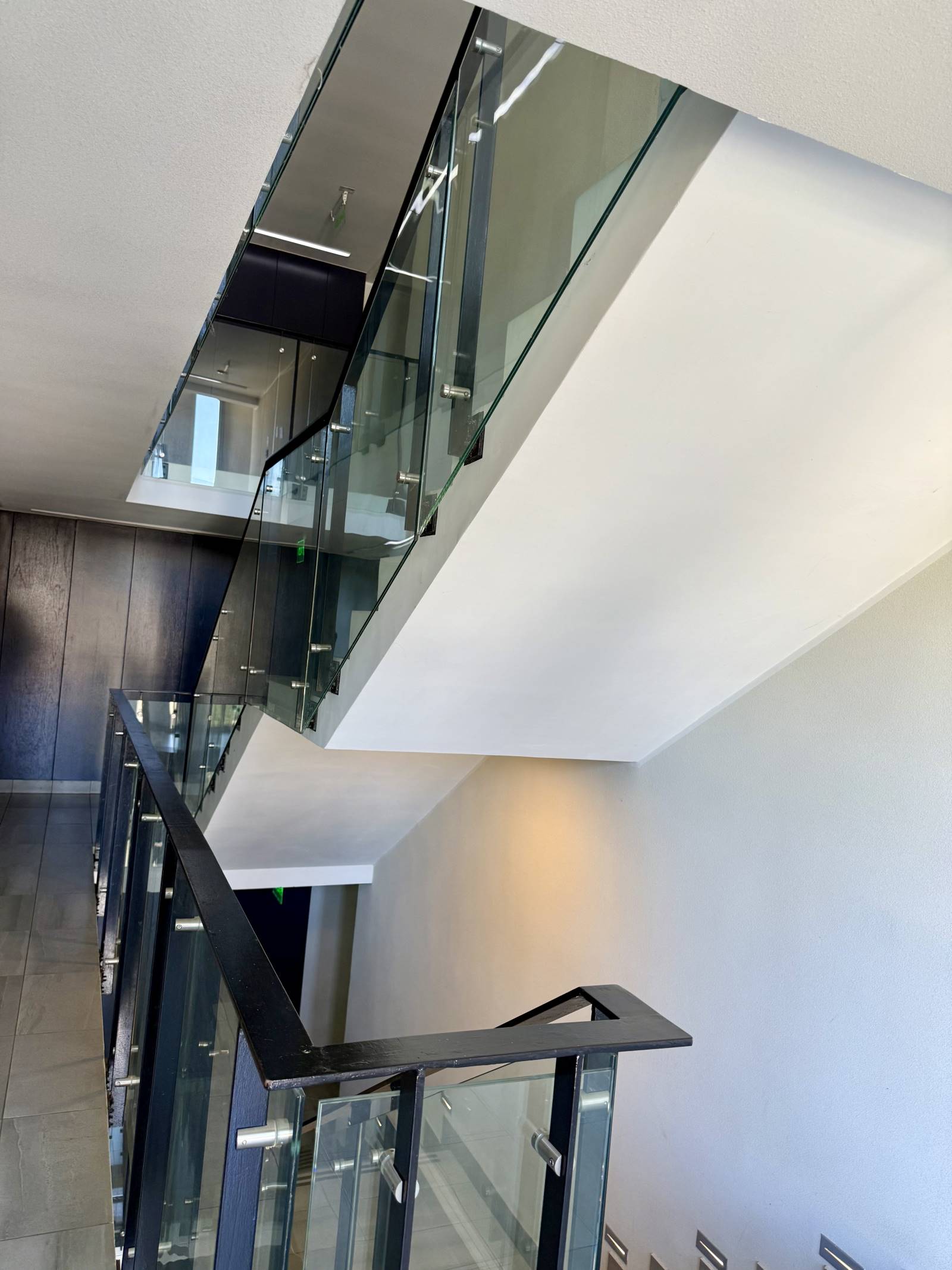 Escalera interior con barandas de vidrio y estructura metálica.