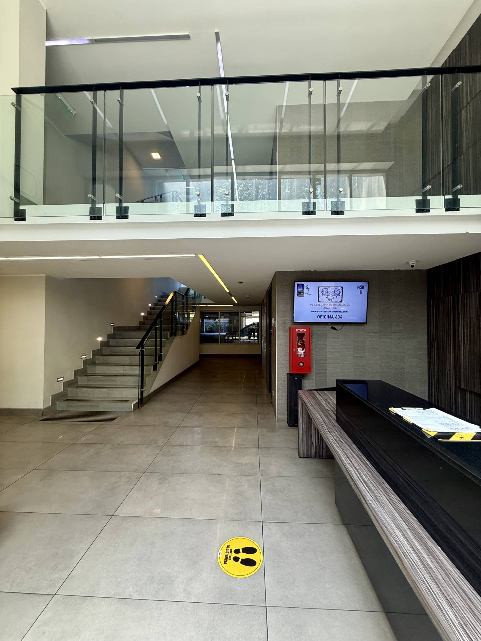 Recepción del edificio con mesón de atención y escalera.