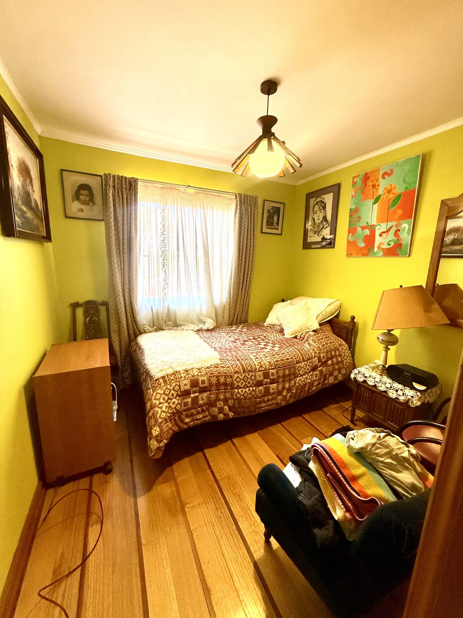 Dormitorio secundario con cama individual y ventana con cortinas