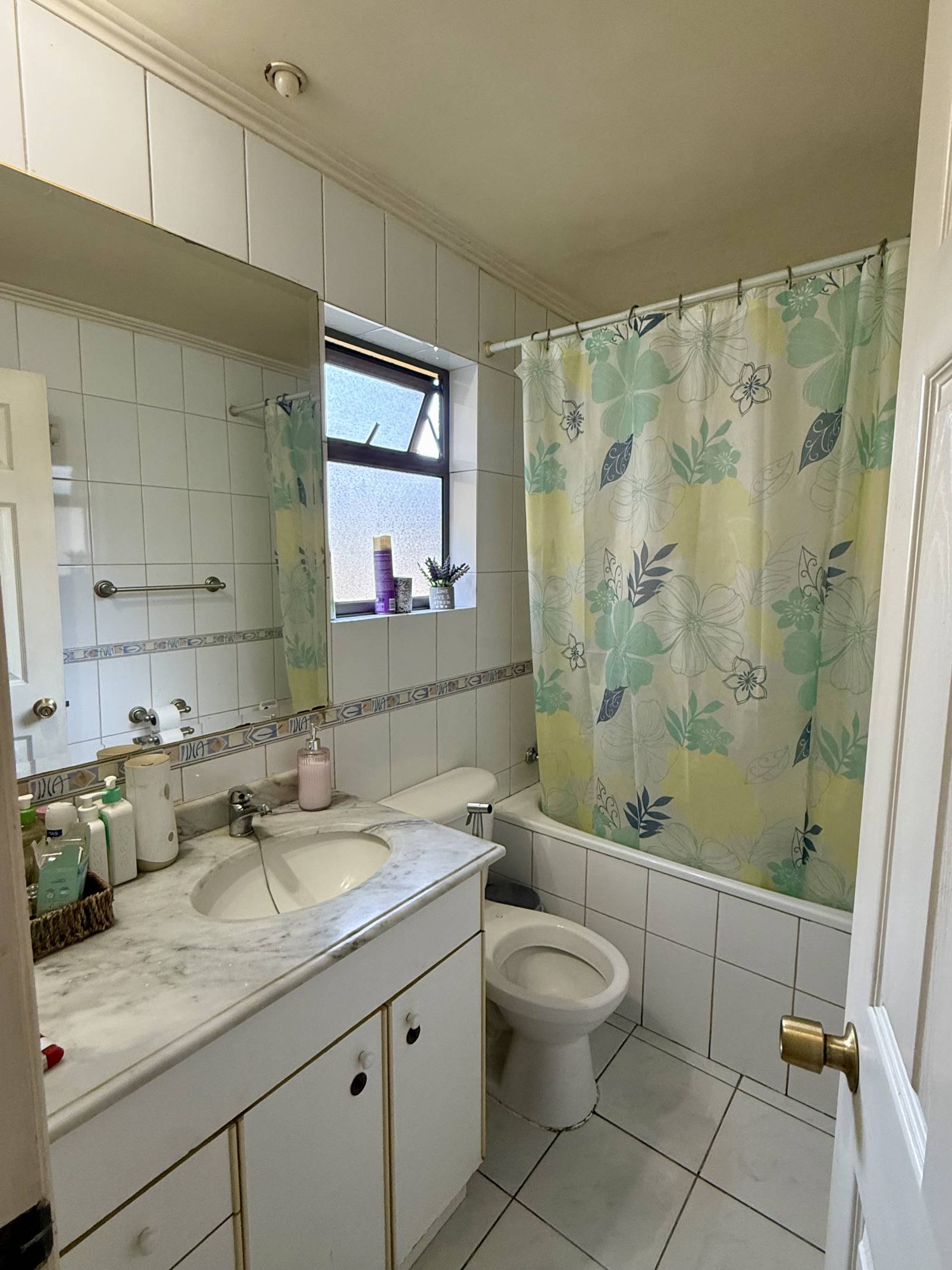 Baño completo con tina, vanitorio de mármol y ventana.