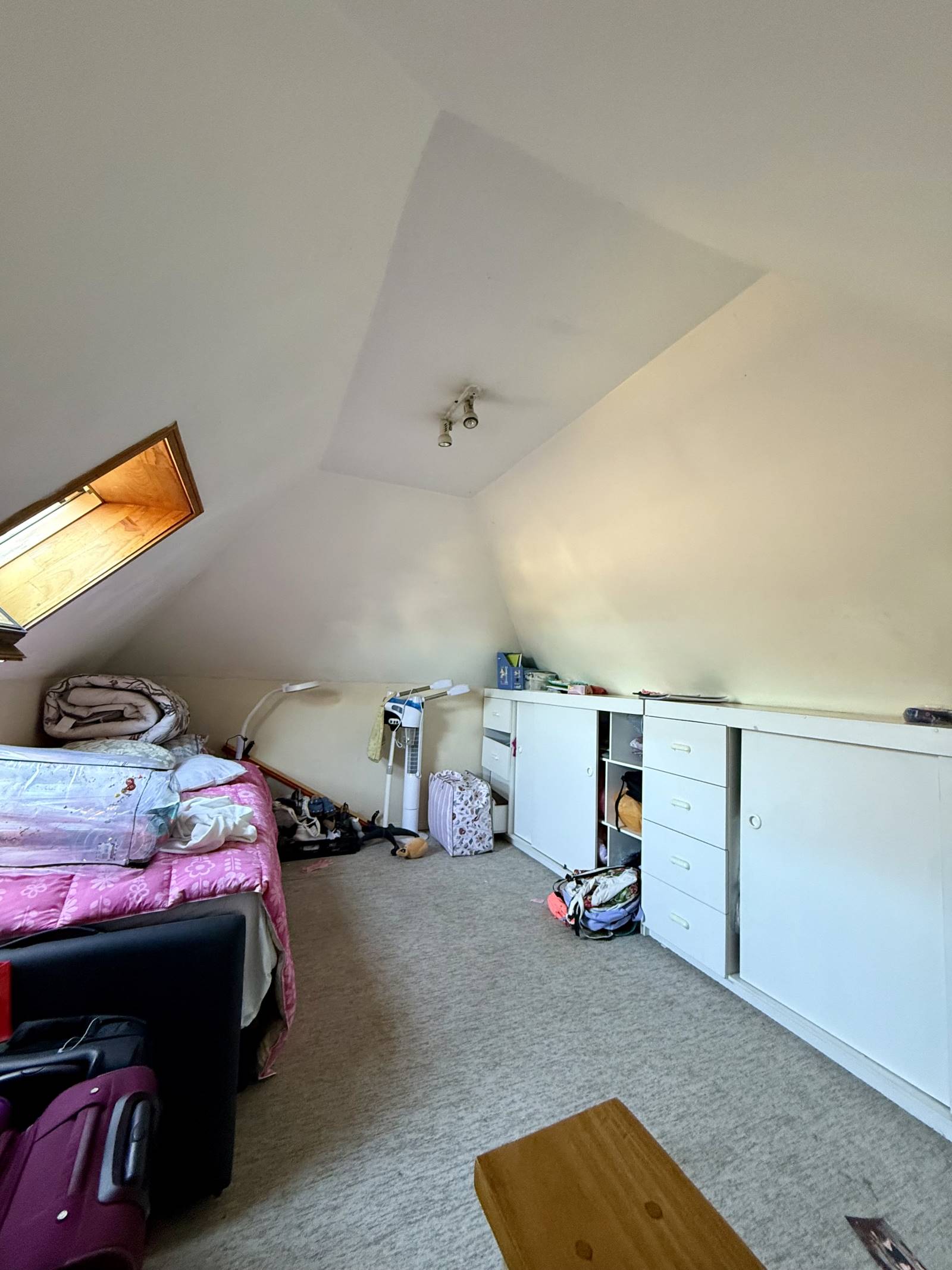 Dormitorio en mansarda con techo inclinado y muebles empotrados.