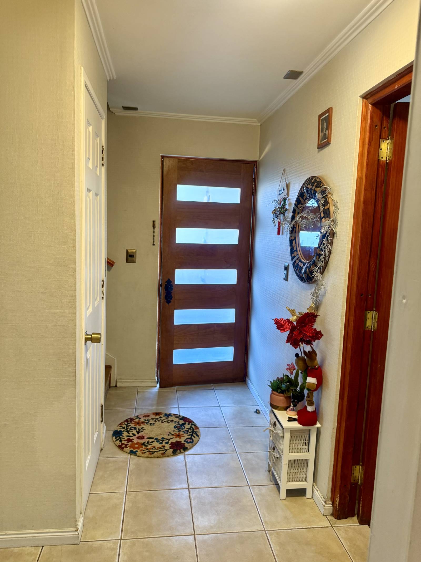 Hall de entrada con puerta de madera y piso cerámico.