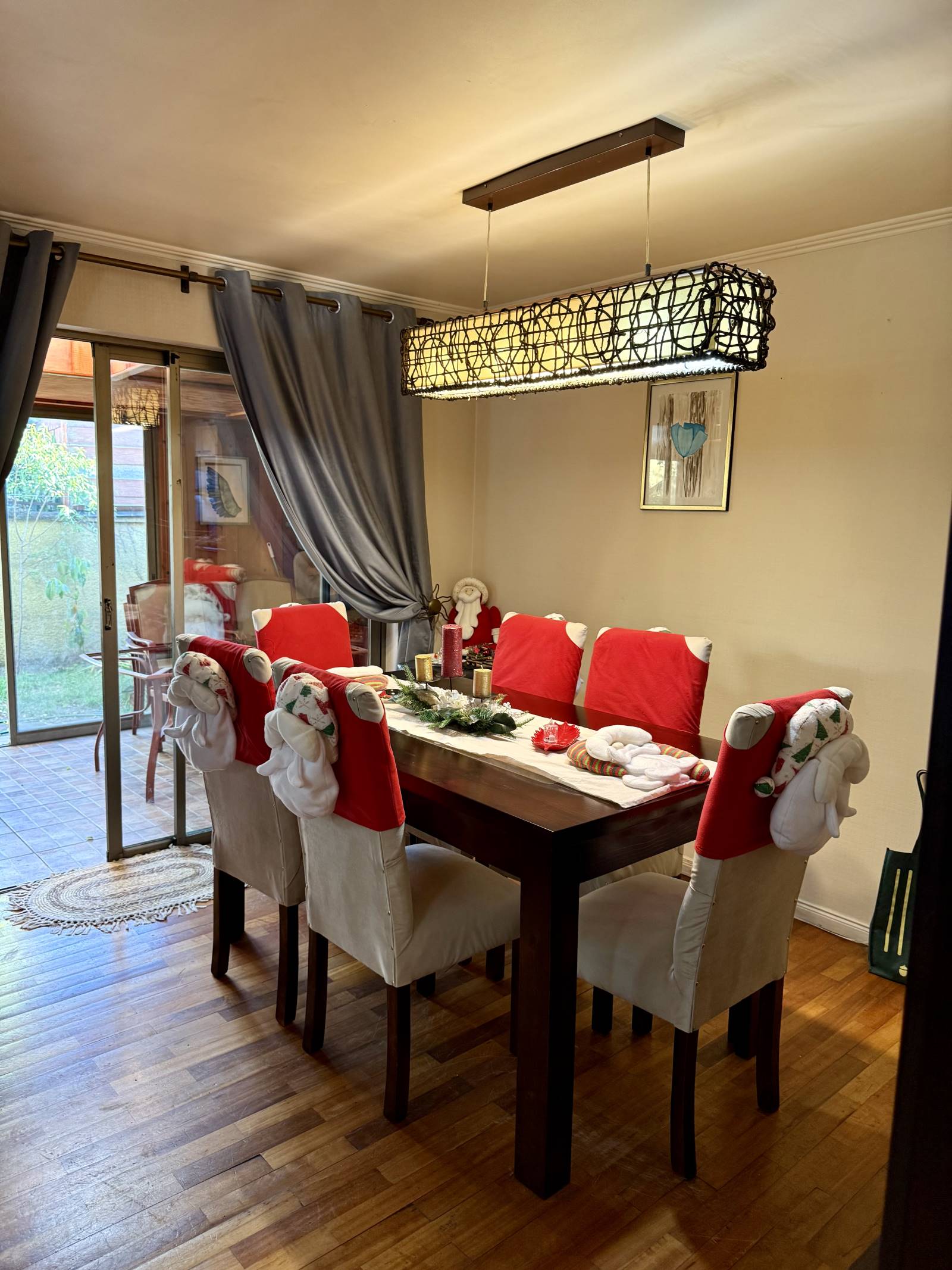 Comedor de madera con moderna lámpara colgante y ventanal.
