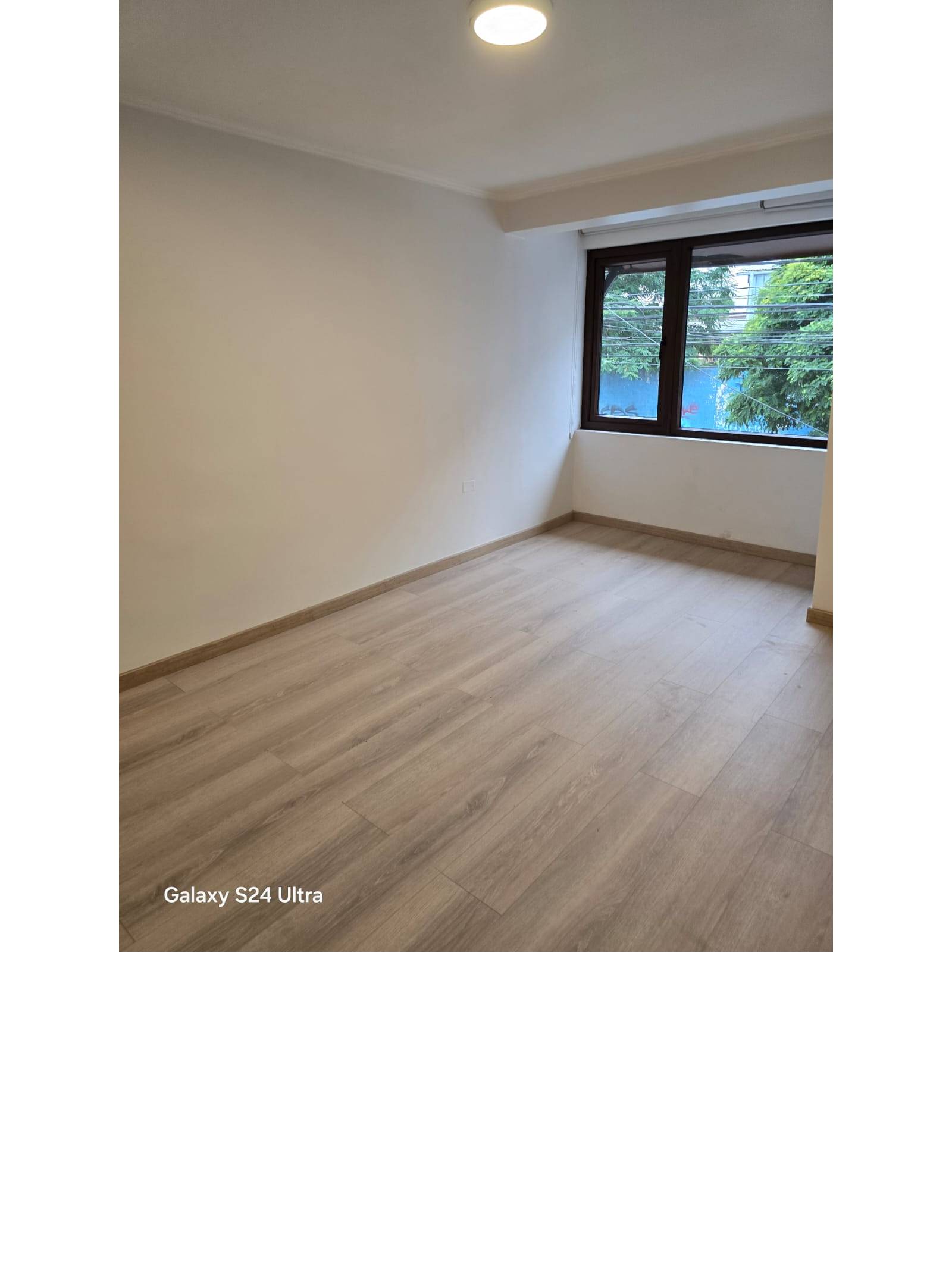 Dormitorio luminoso con ventana amplia y piso flotante.