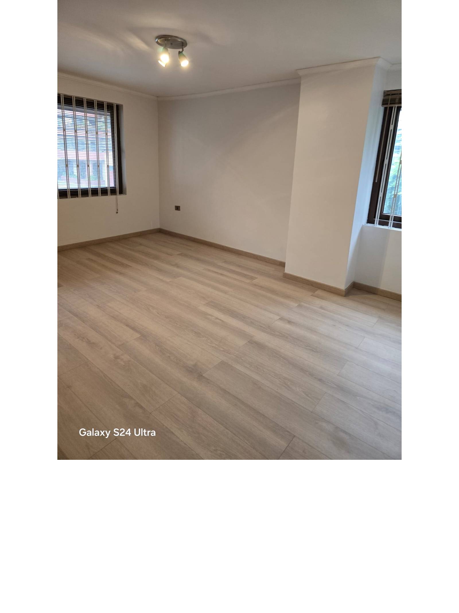 Habitación espaciosa con piso flotante y ventanas con reja.