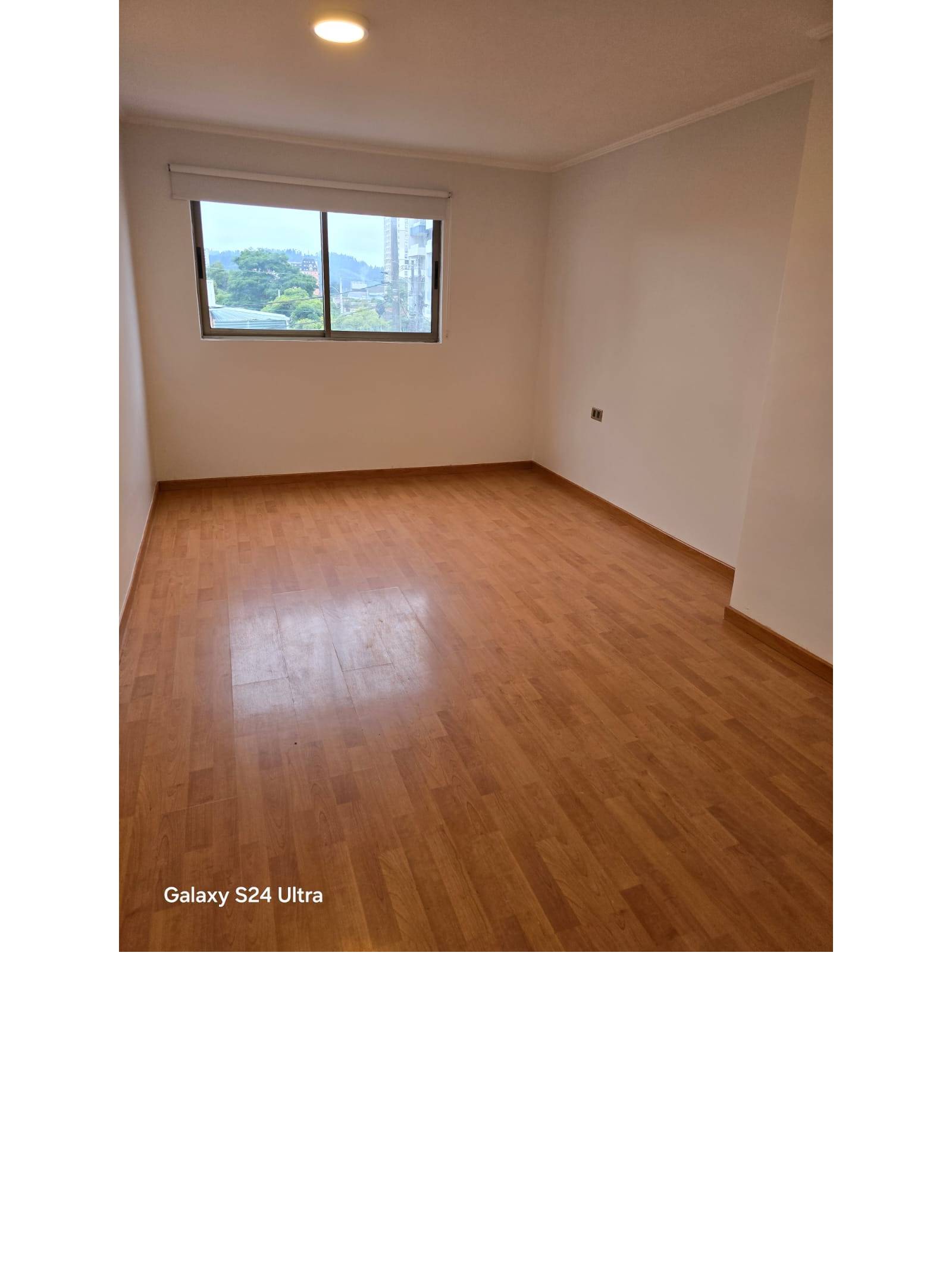 Habitación vacía con piso flotante y vista despejada exterior.