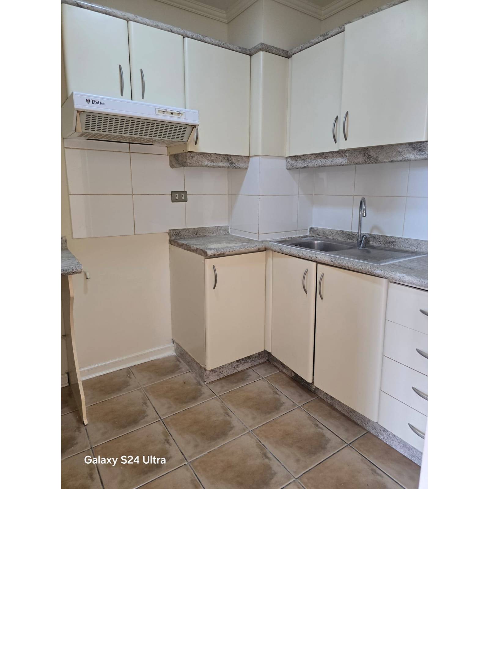 Cocina equipada con muebles blancos, campana y lavaplatos empotrado