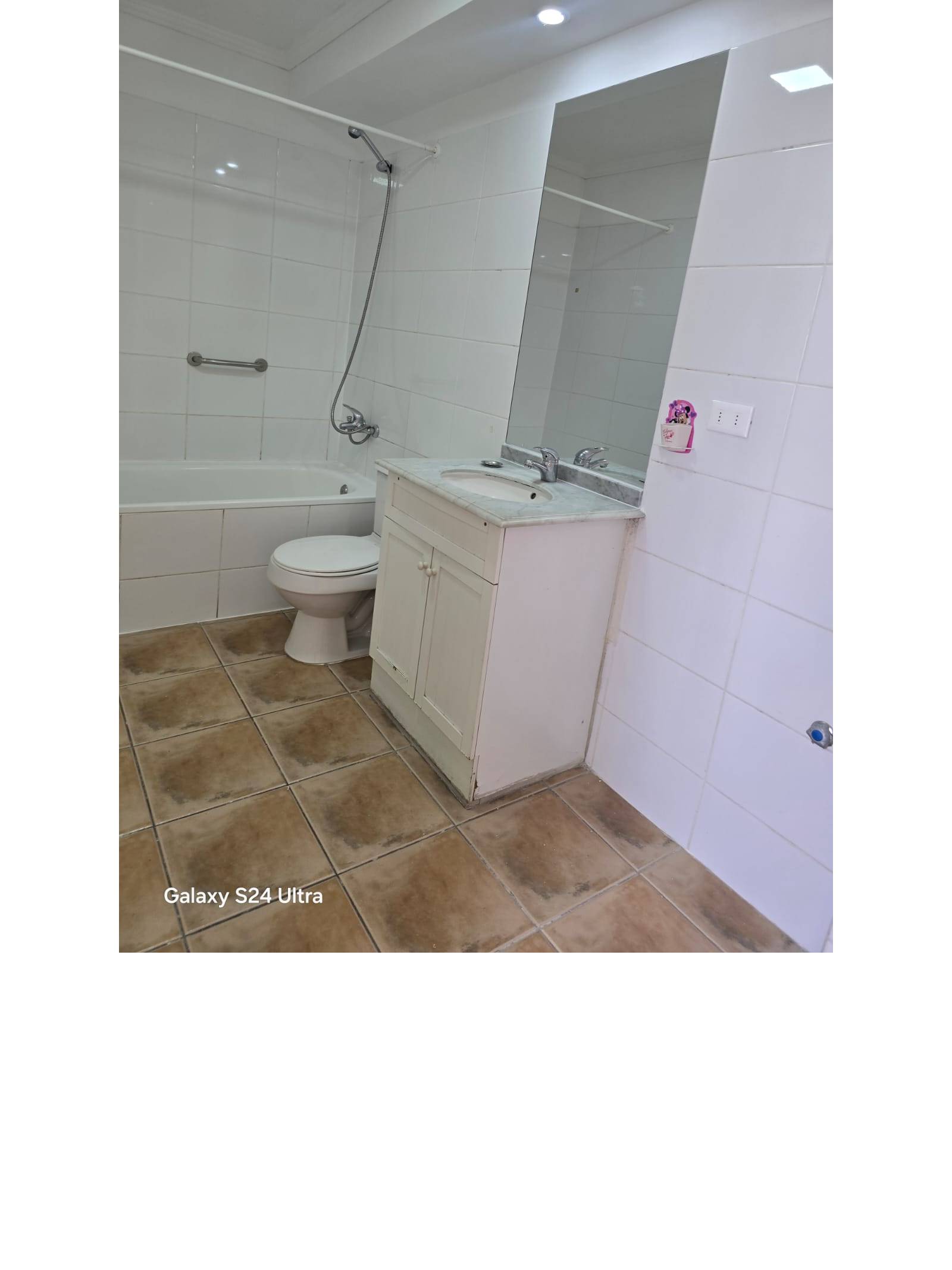 Baño con tina, vanitorio blanco y paredes de cerámica