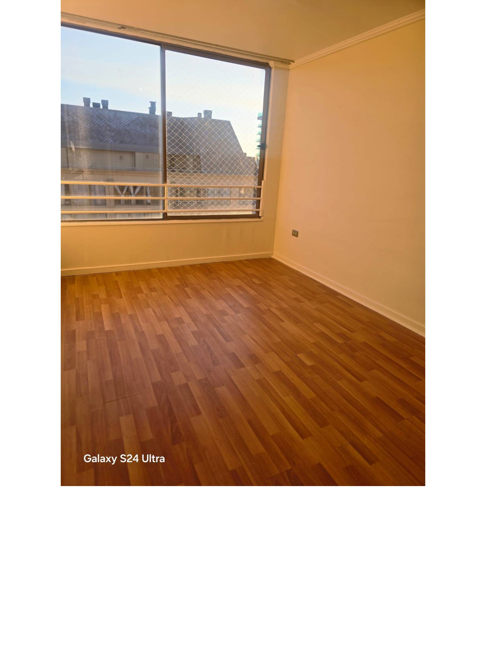 Habitación vacía con piso flotante y amplia ventana
