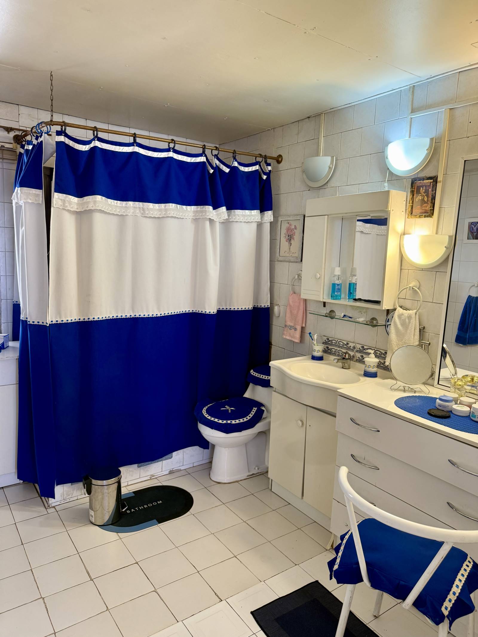 Baño con cortina azul y blanca, vanitorio y espejo.
