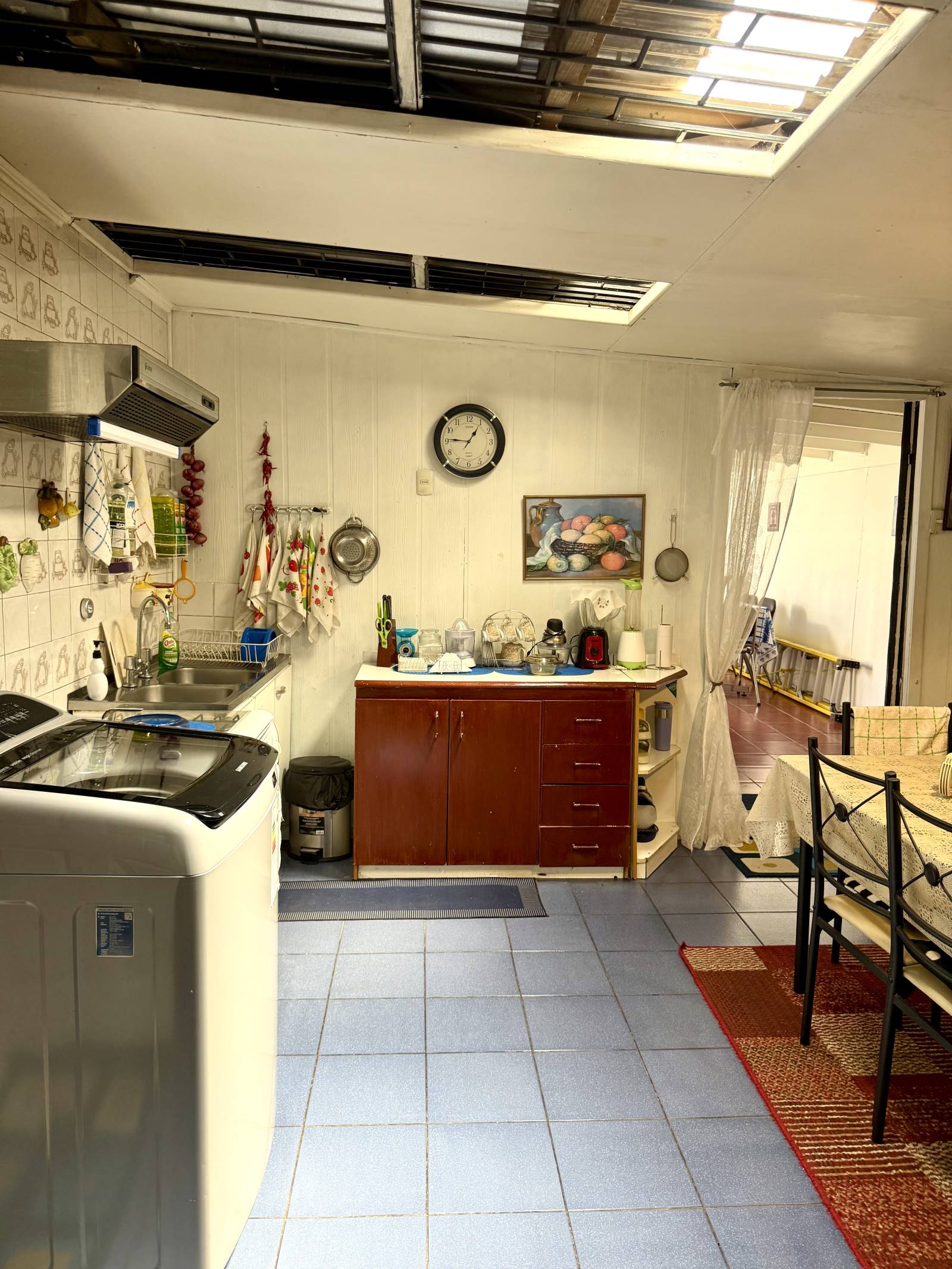 Cocina con muebles de madera, lavaplatos y lavadora.