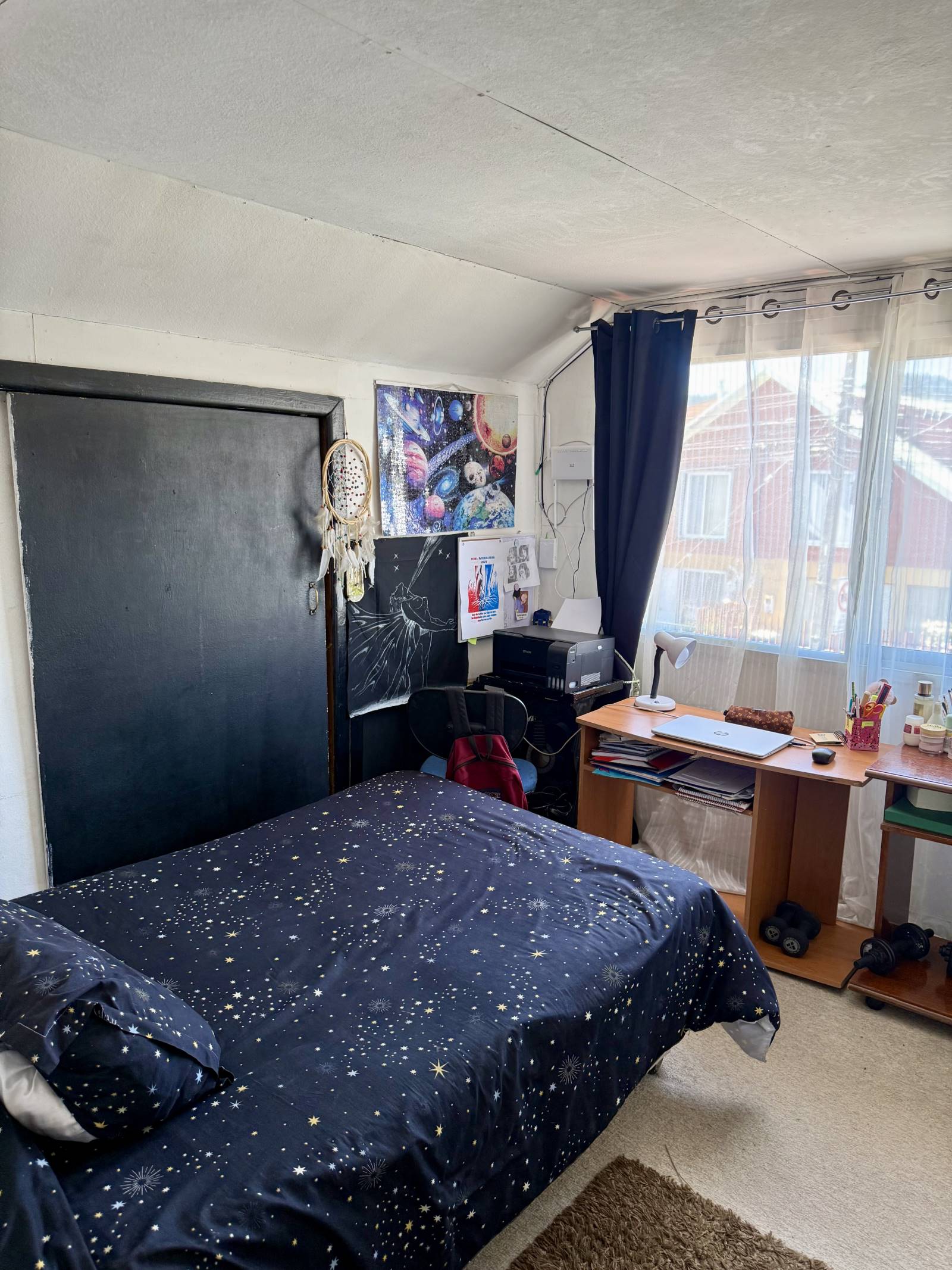 Dormitorio con cama de plaza y media y escritorio iluminado.