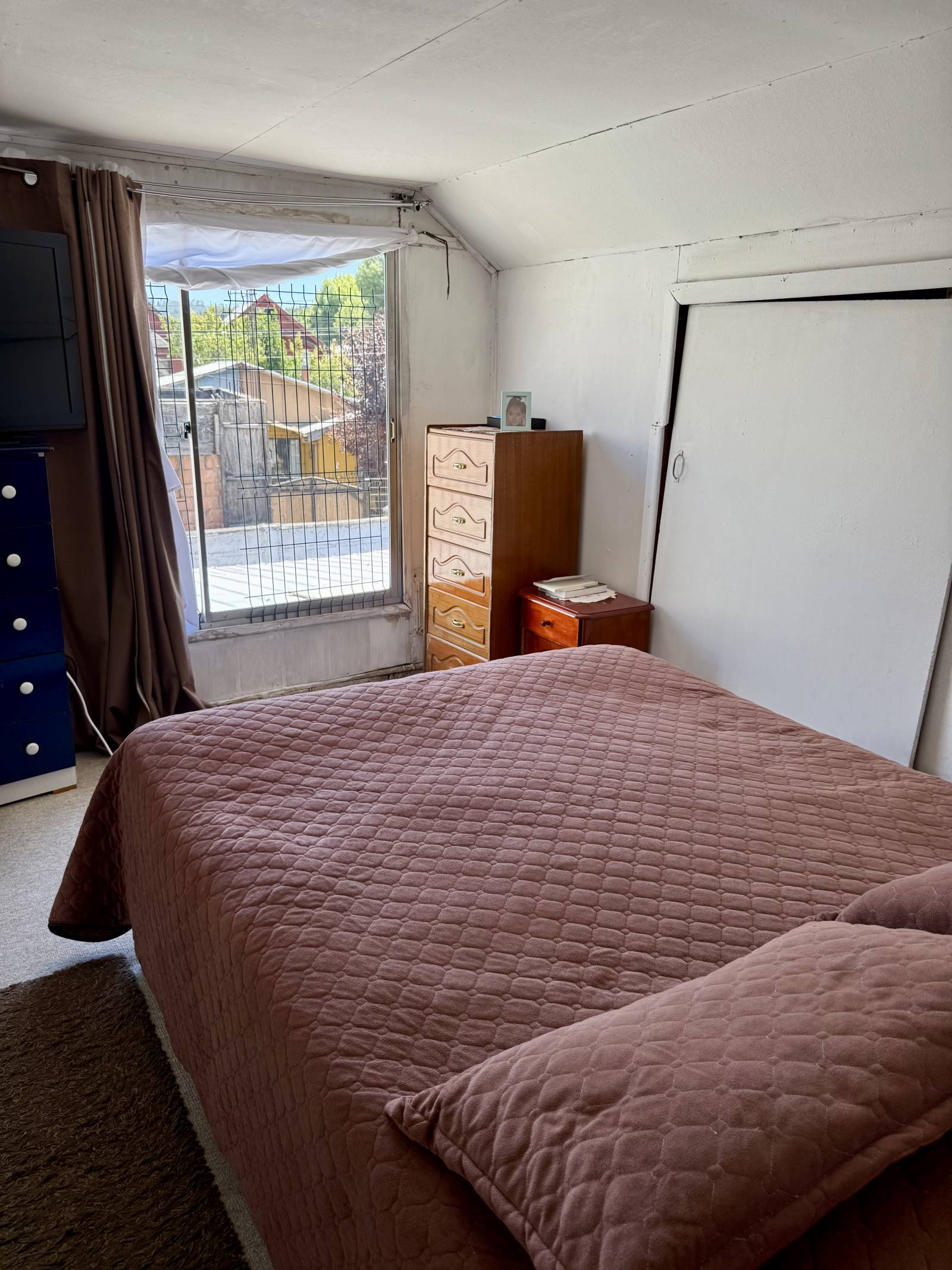 Dormitorio principal con cama matrimonial y ventana al exterior.