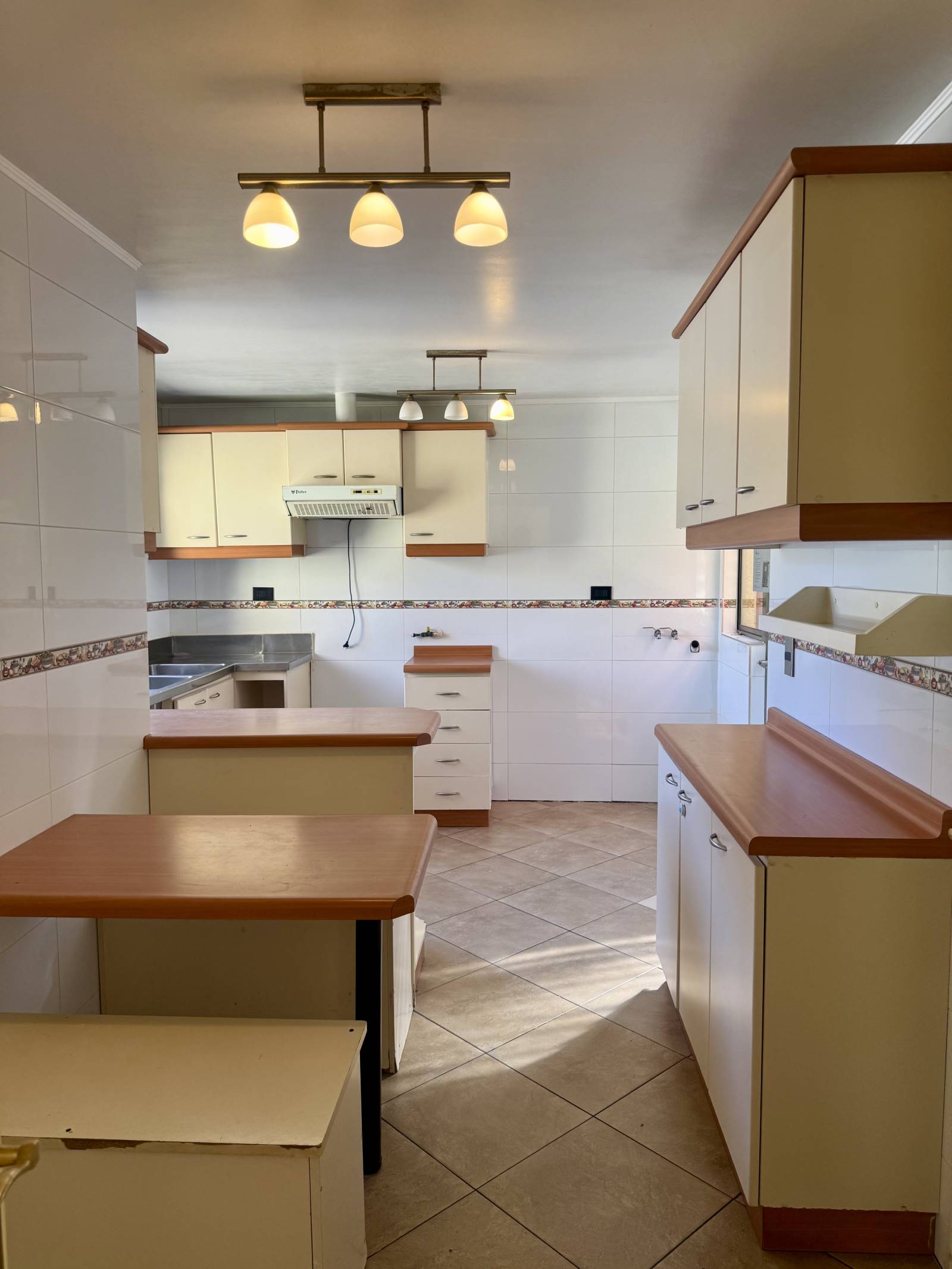 Cocina amplia amoblada con muebles empotrados y piso cerámico.