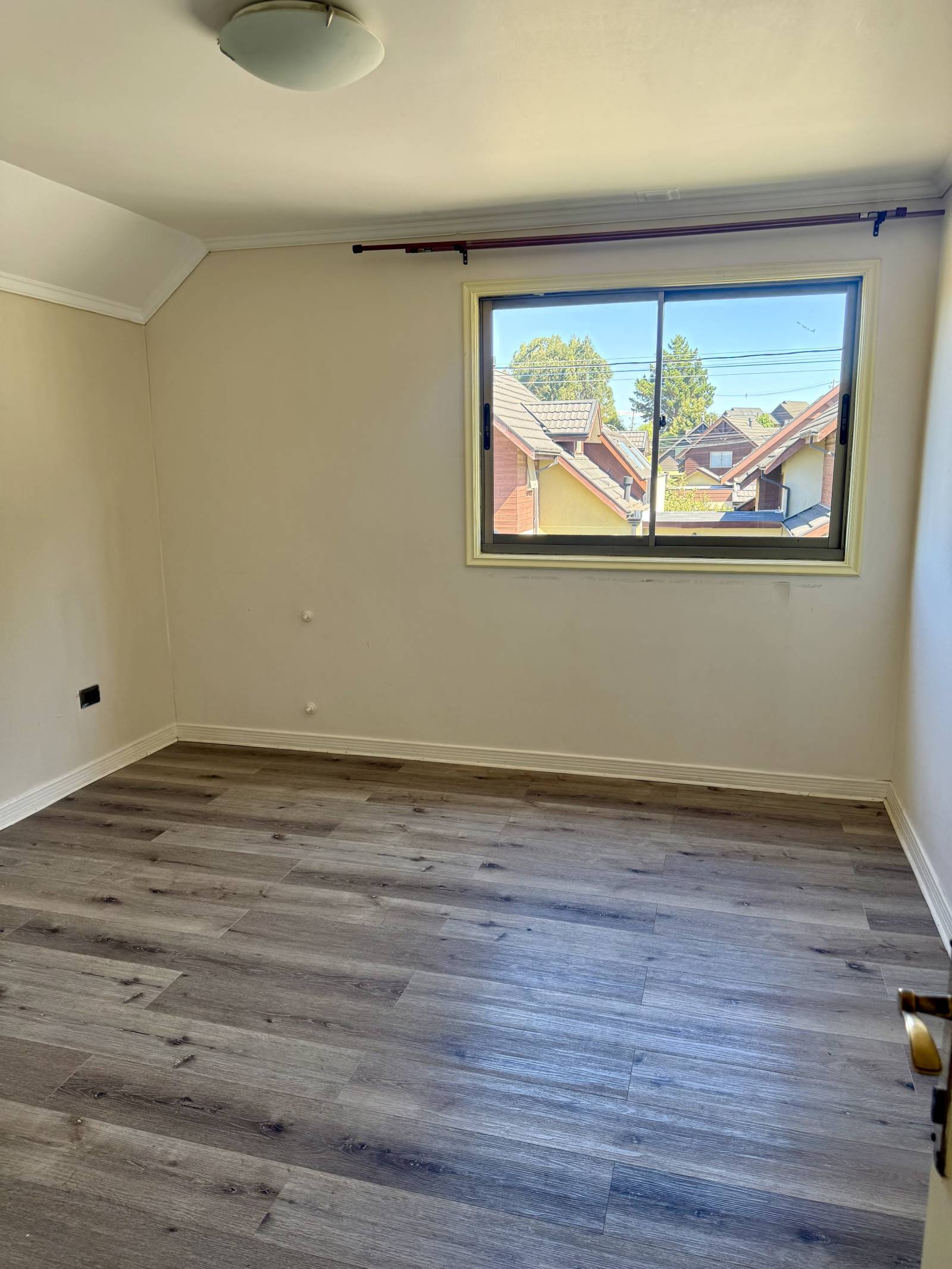 Dormitorio principal con ventana al exterior y piso laminado.