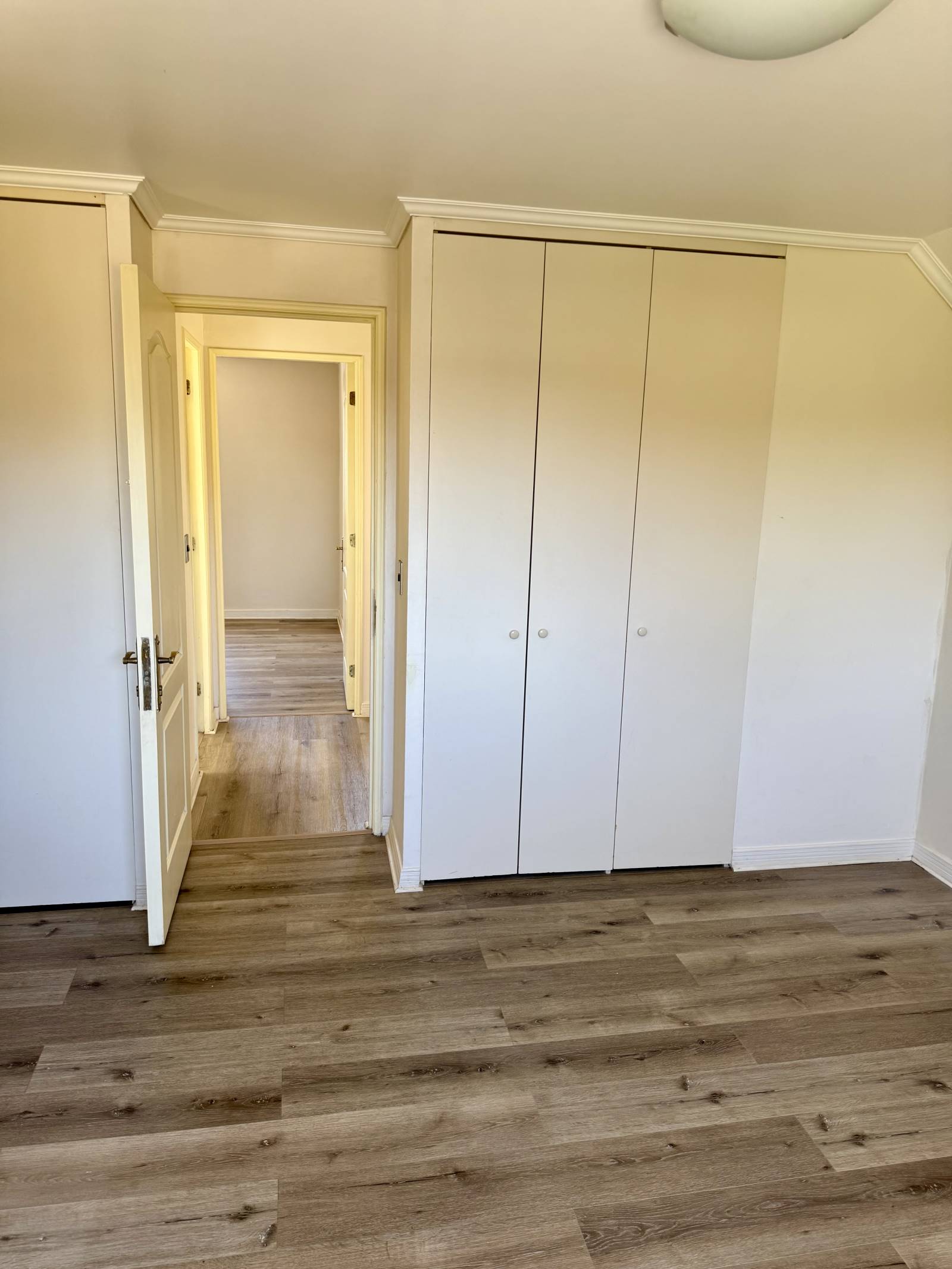 Dormitorio con closet empotrado de tres puertas y pasillo.
