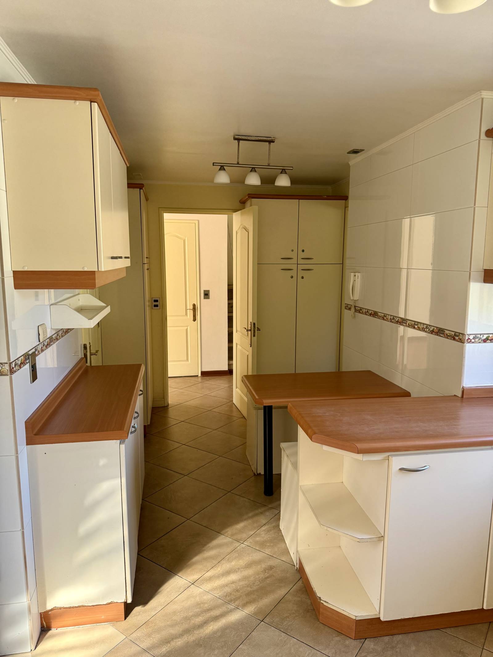 Cocina con mesones, muebles empotrados y puerta de servicio.