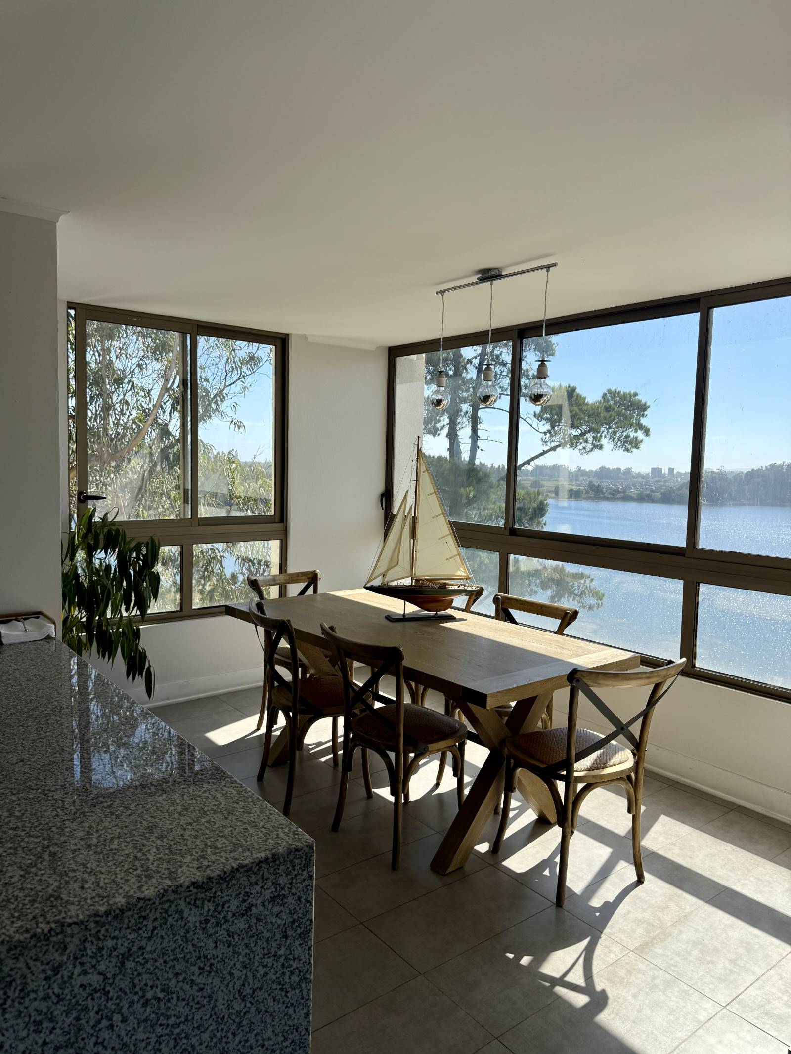 Comedor con mesa de madera y amplio ventanal con vista a la laguna