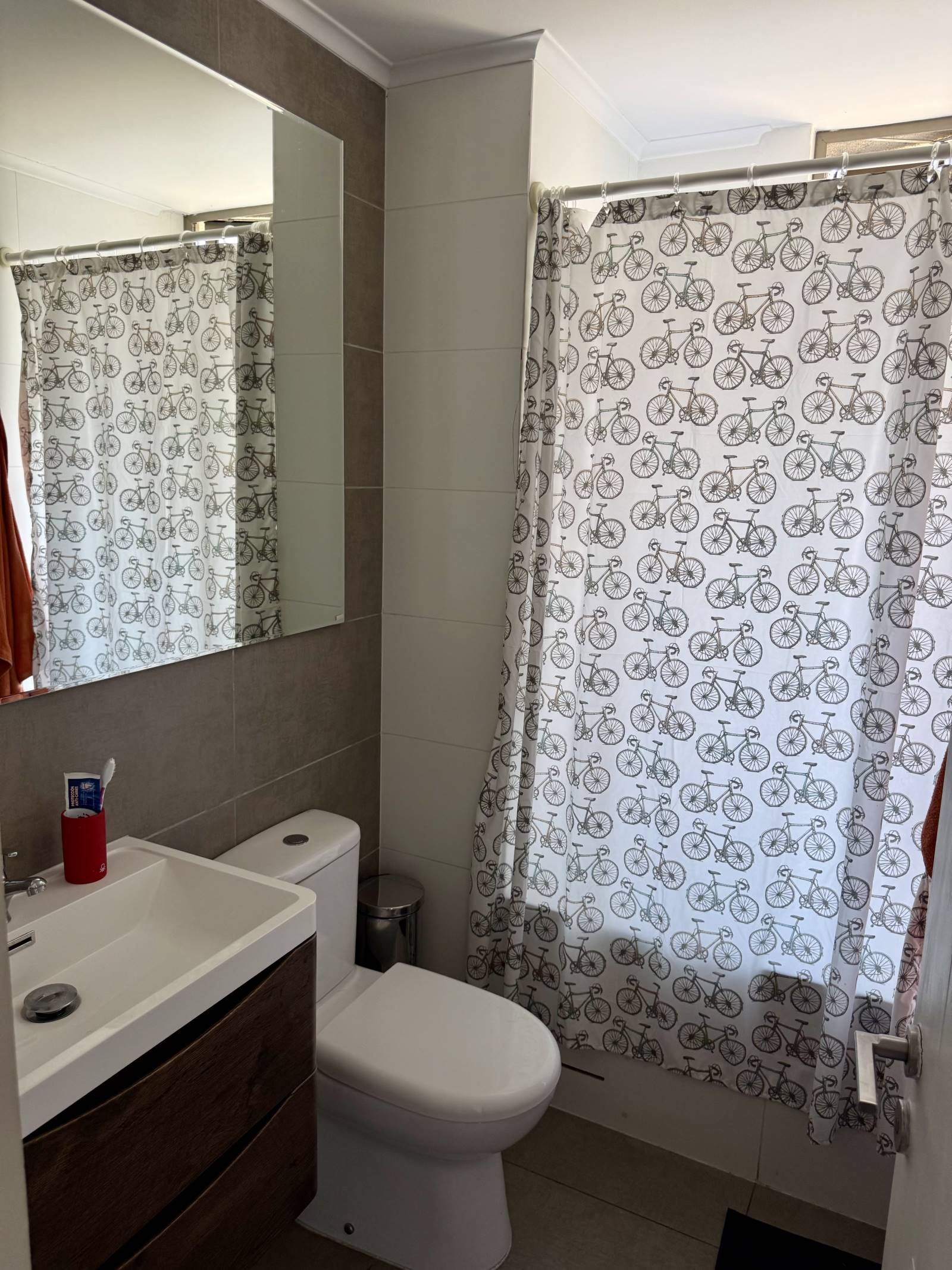 Baño con vanitorio moderno, inodoro y cortina decorativa