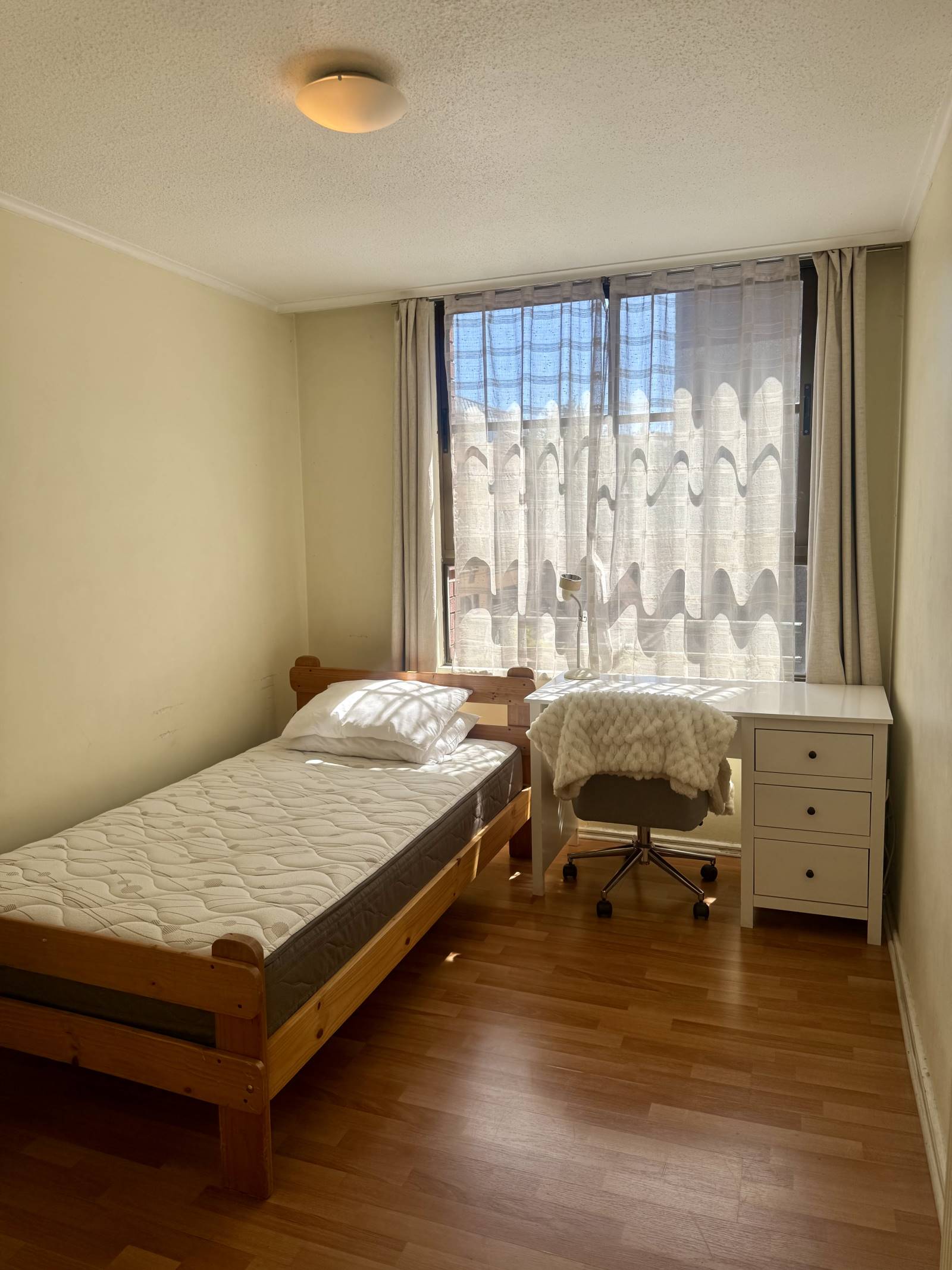 Dormitorio amoblado con cama individual y escritorio junto a la ventana