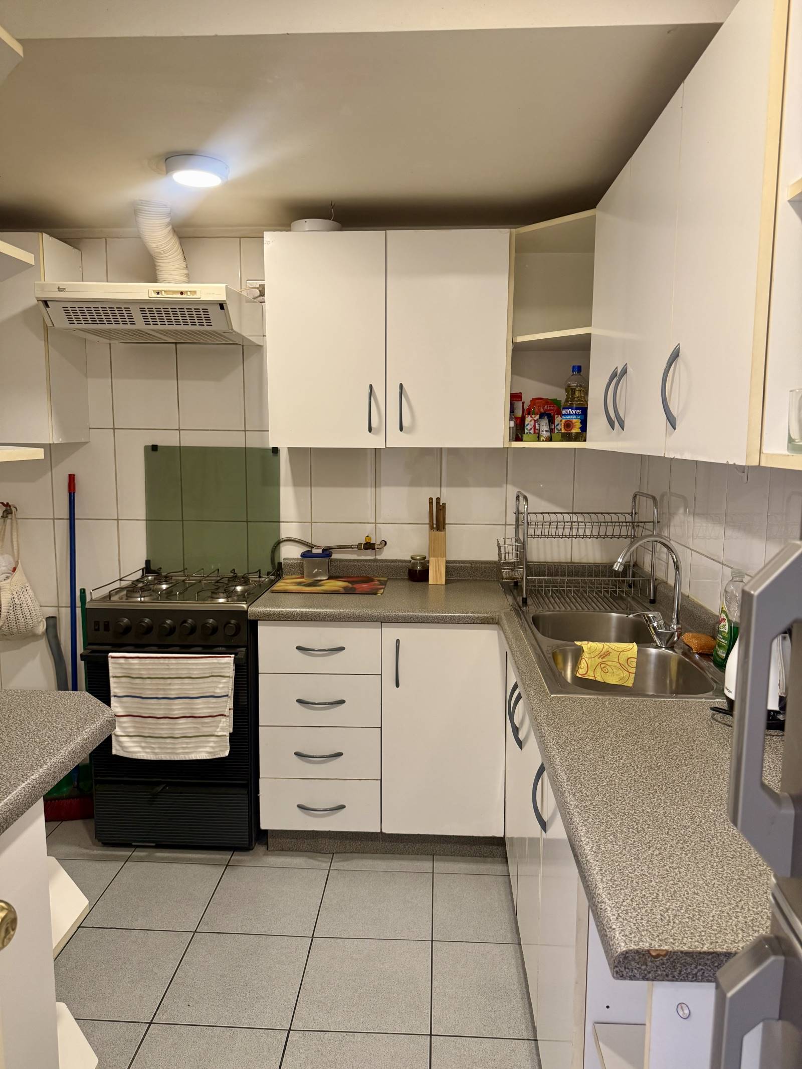 Cocina equipada con muebles blancos, cocina a gas y lavaplatos