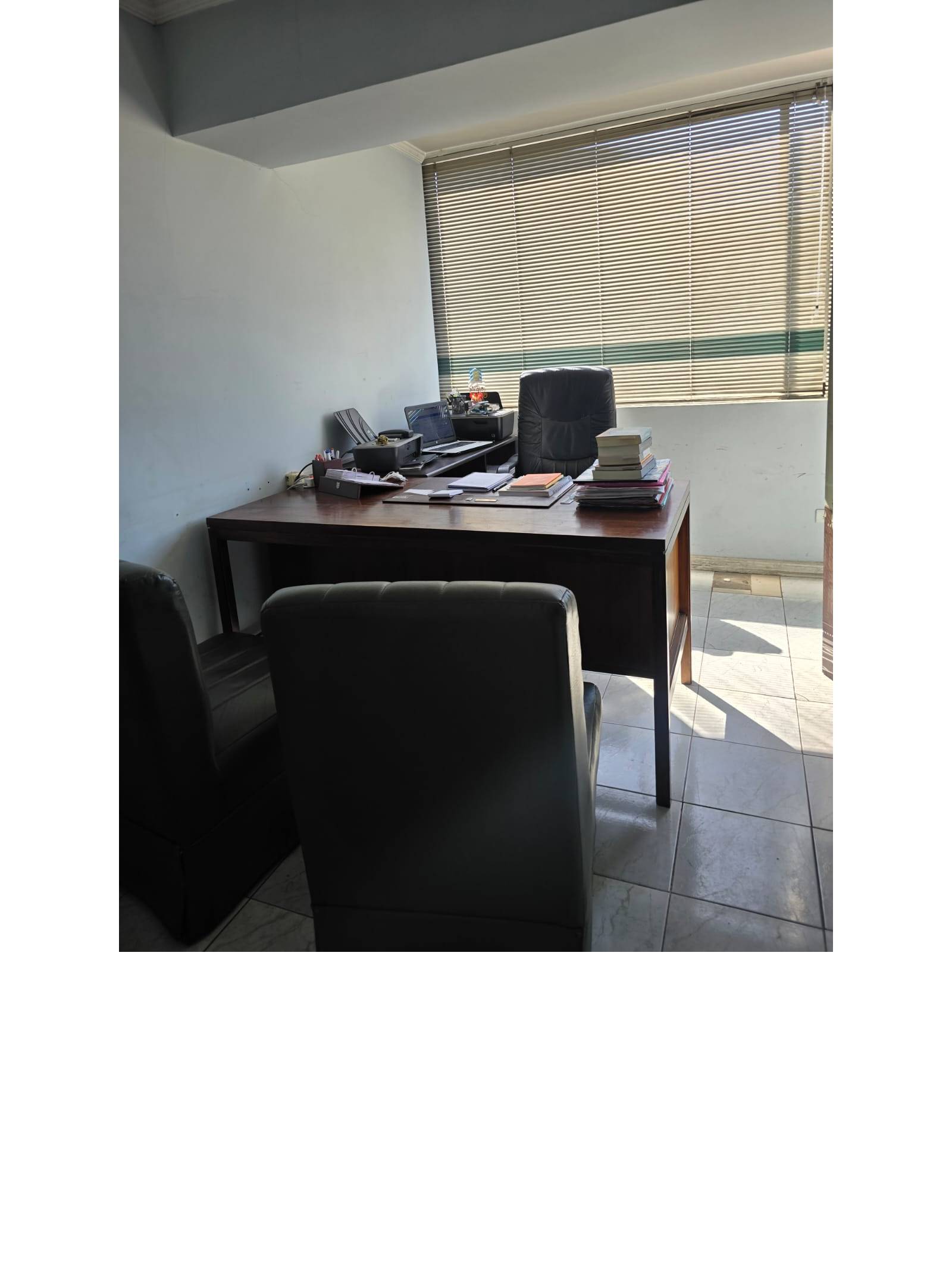 Oficina privada con escritorio y amplio ventanal.