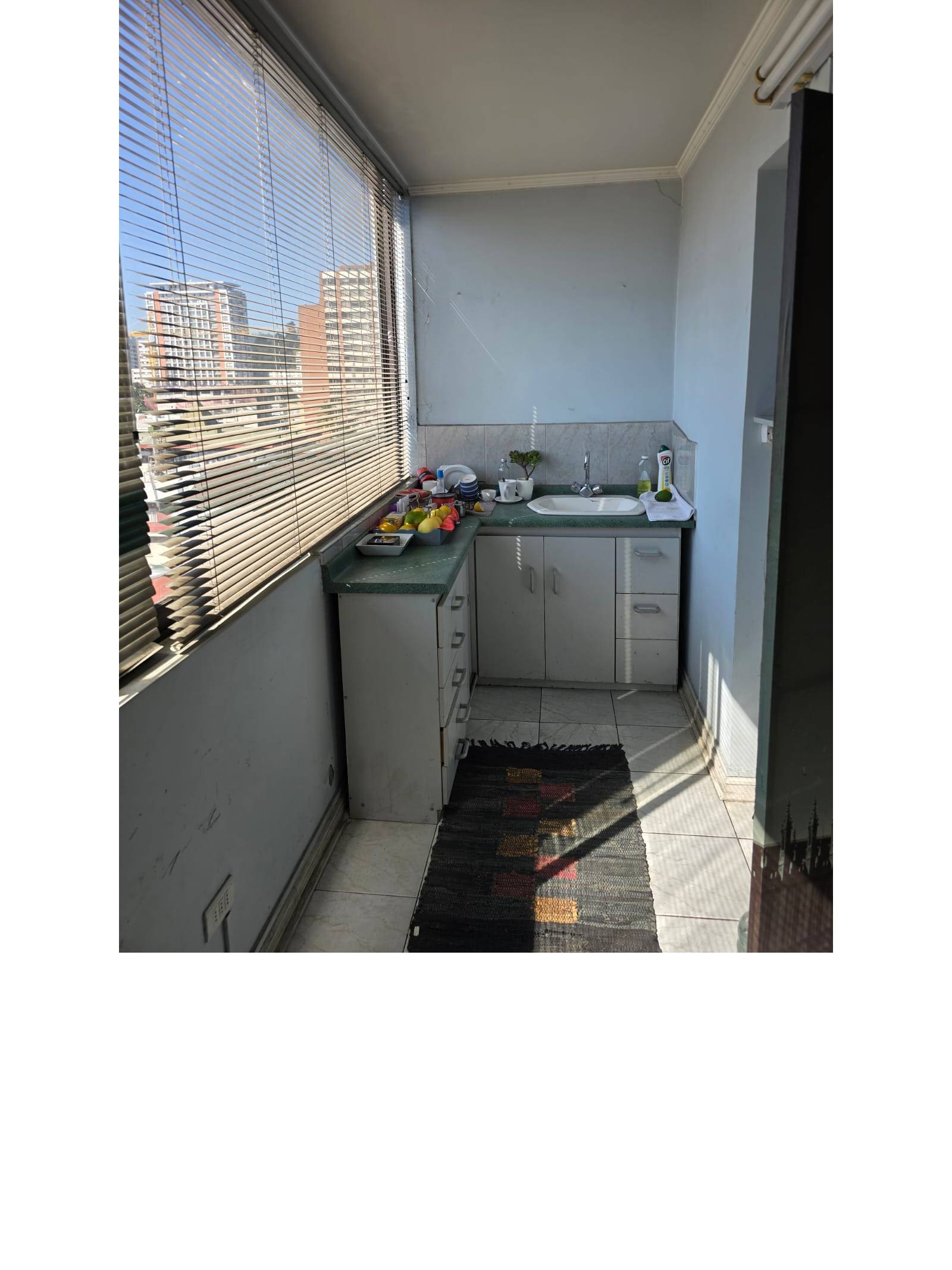 Kitchenette con lavaplatos y ventanal con vista.