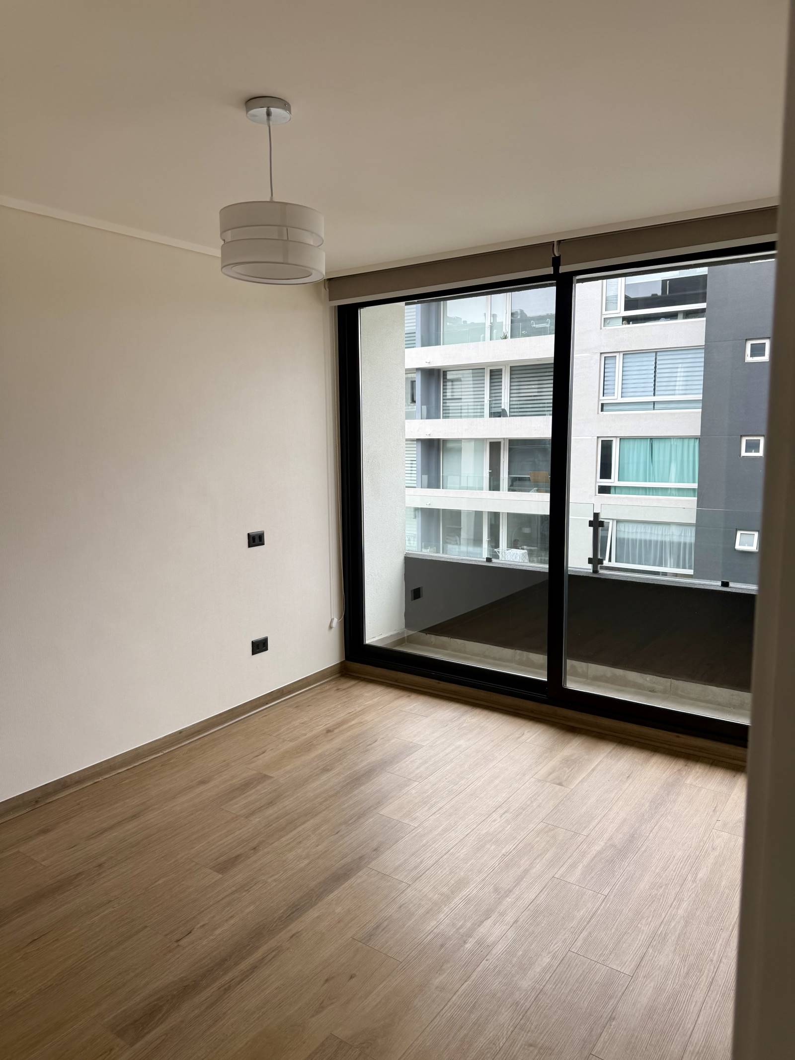 Dormitorio vacío con piso flotante y ventanal completo al exterior.