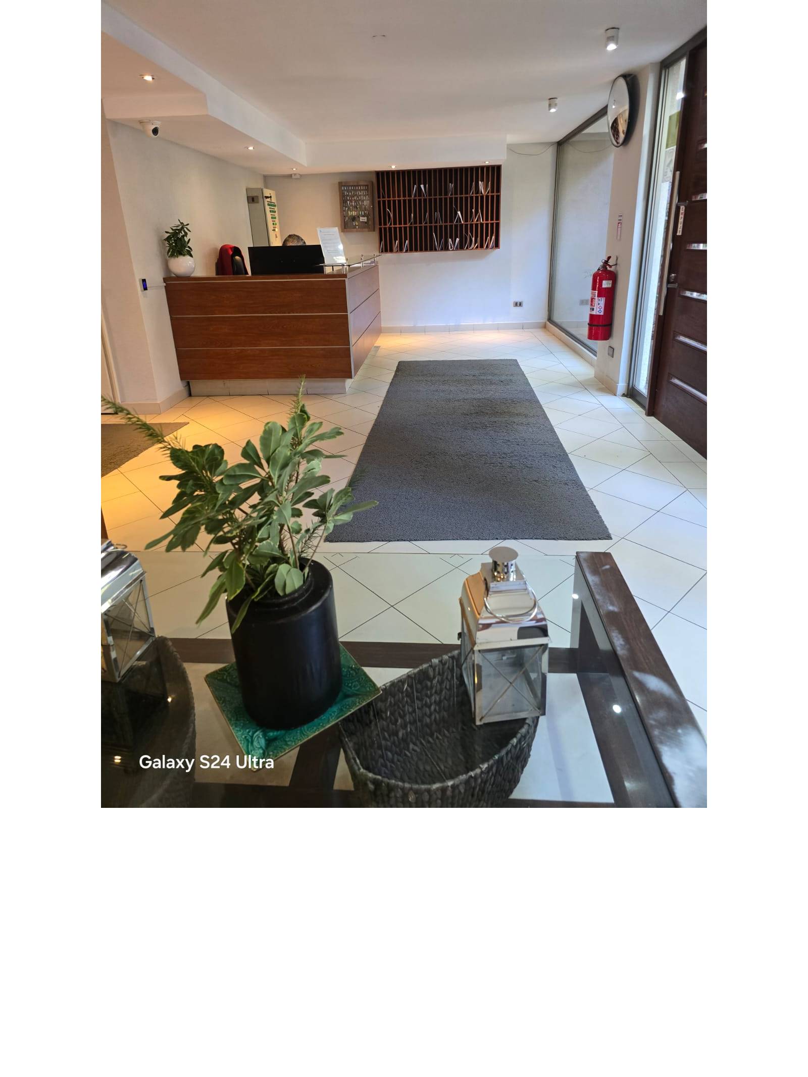 Recepción del edificio con mesón de conserjería y alfombra