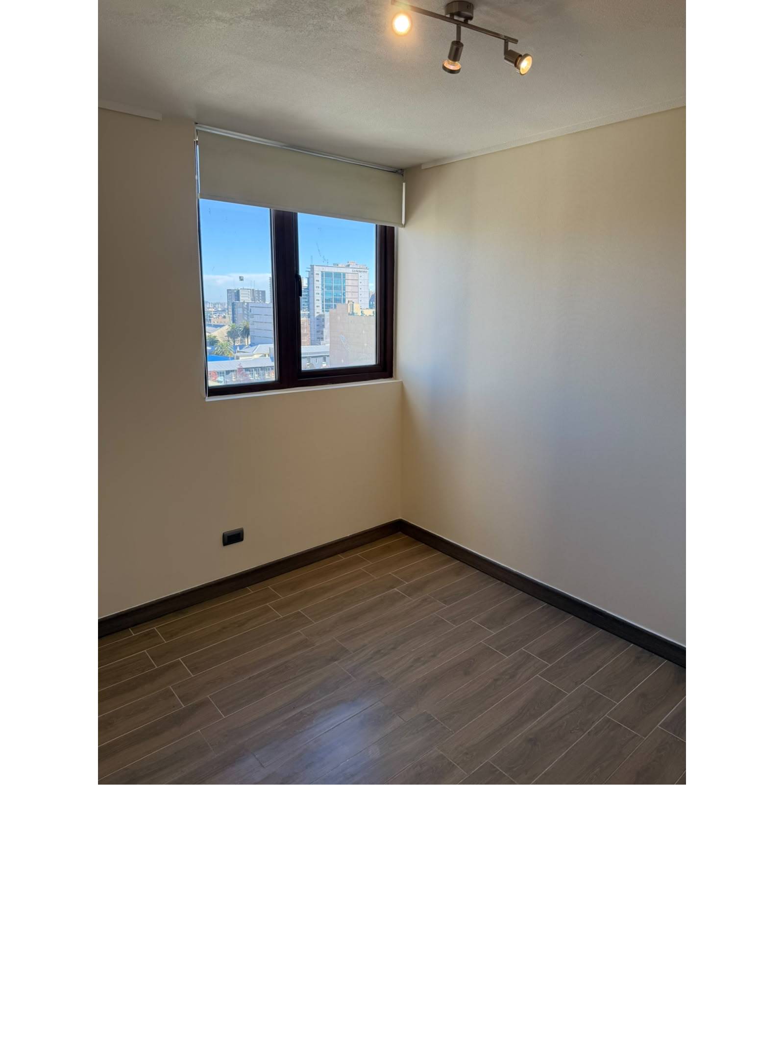 Segundo dormitorio con piso de madera y ventana exterior.