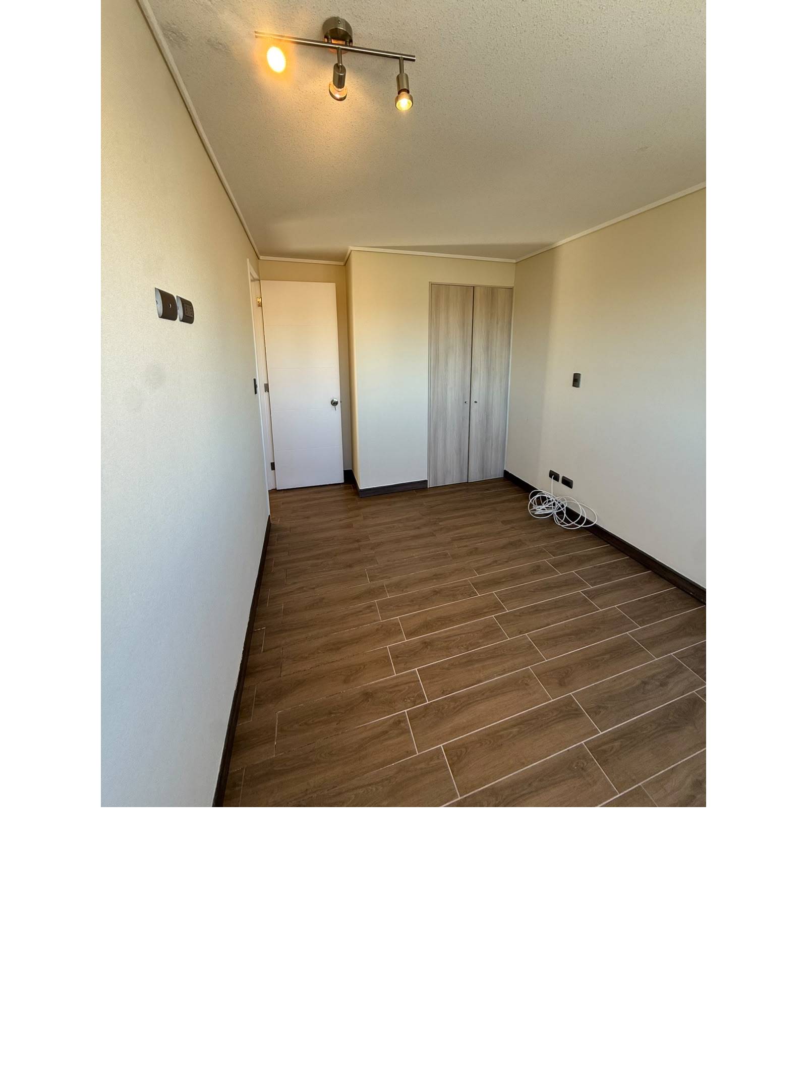 Vista interior del dormitorio hacia clóset empotrado y puerta.