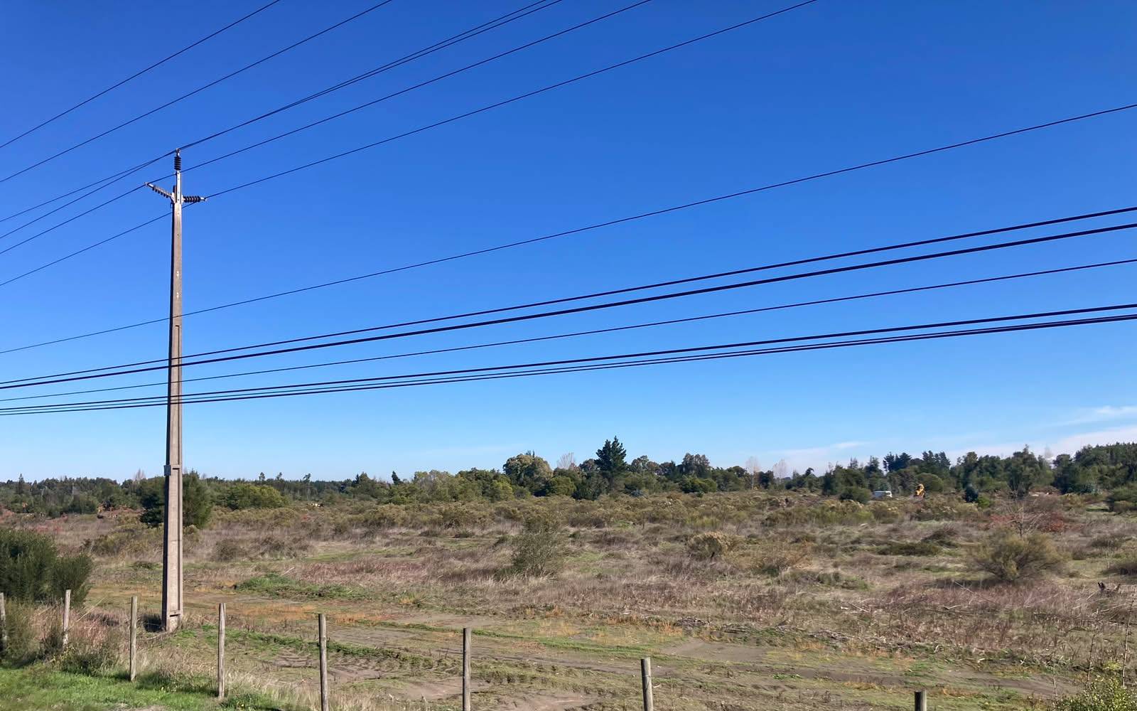 Extensión de campo rústico con poste eléctrico en primer plano