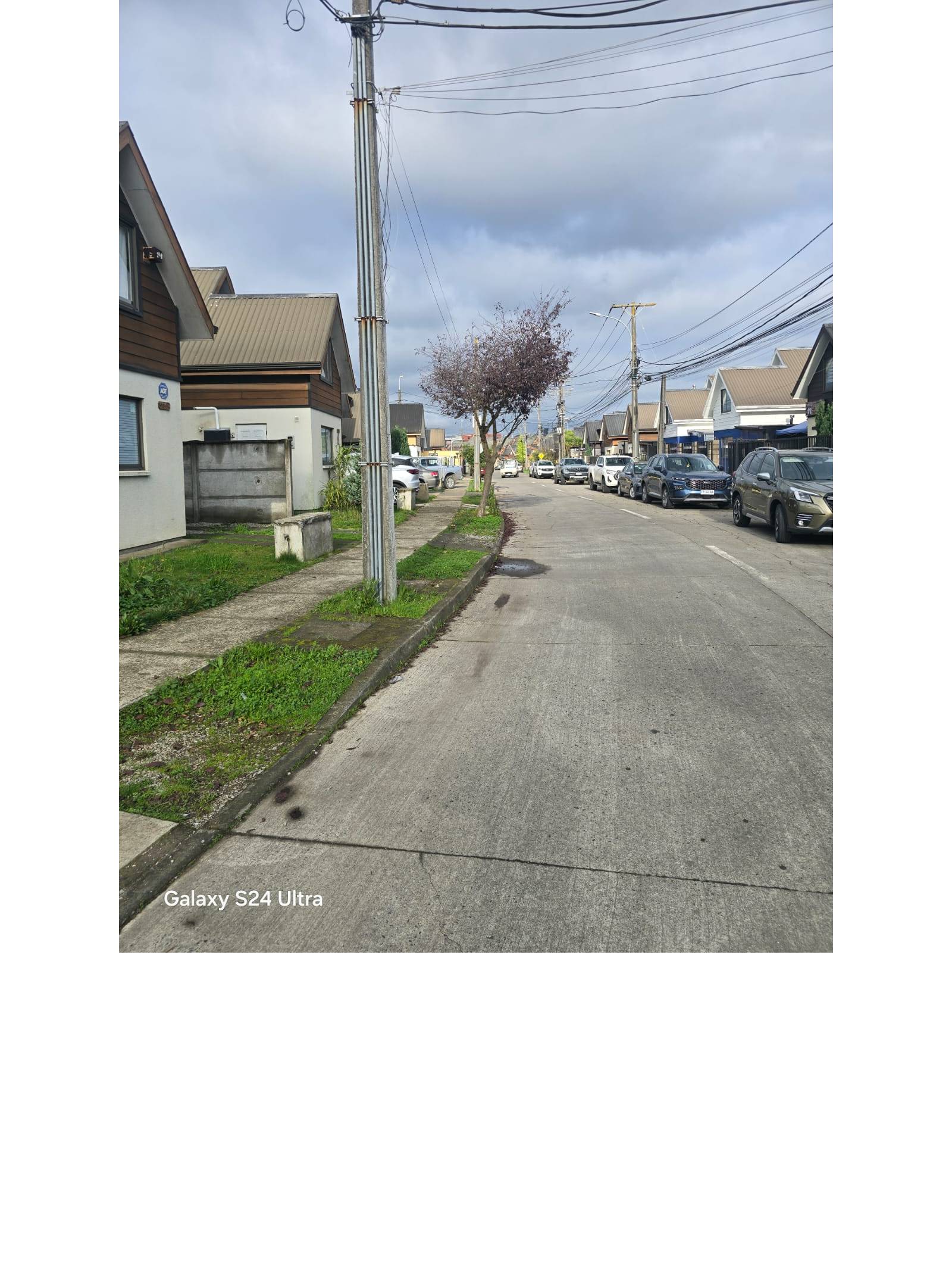 Calle residencial con casas pareadas y poste en primer plano