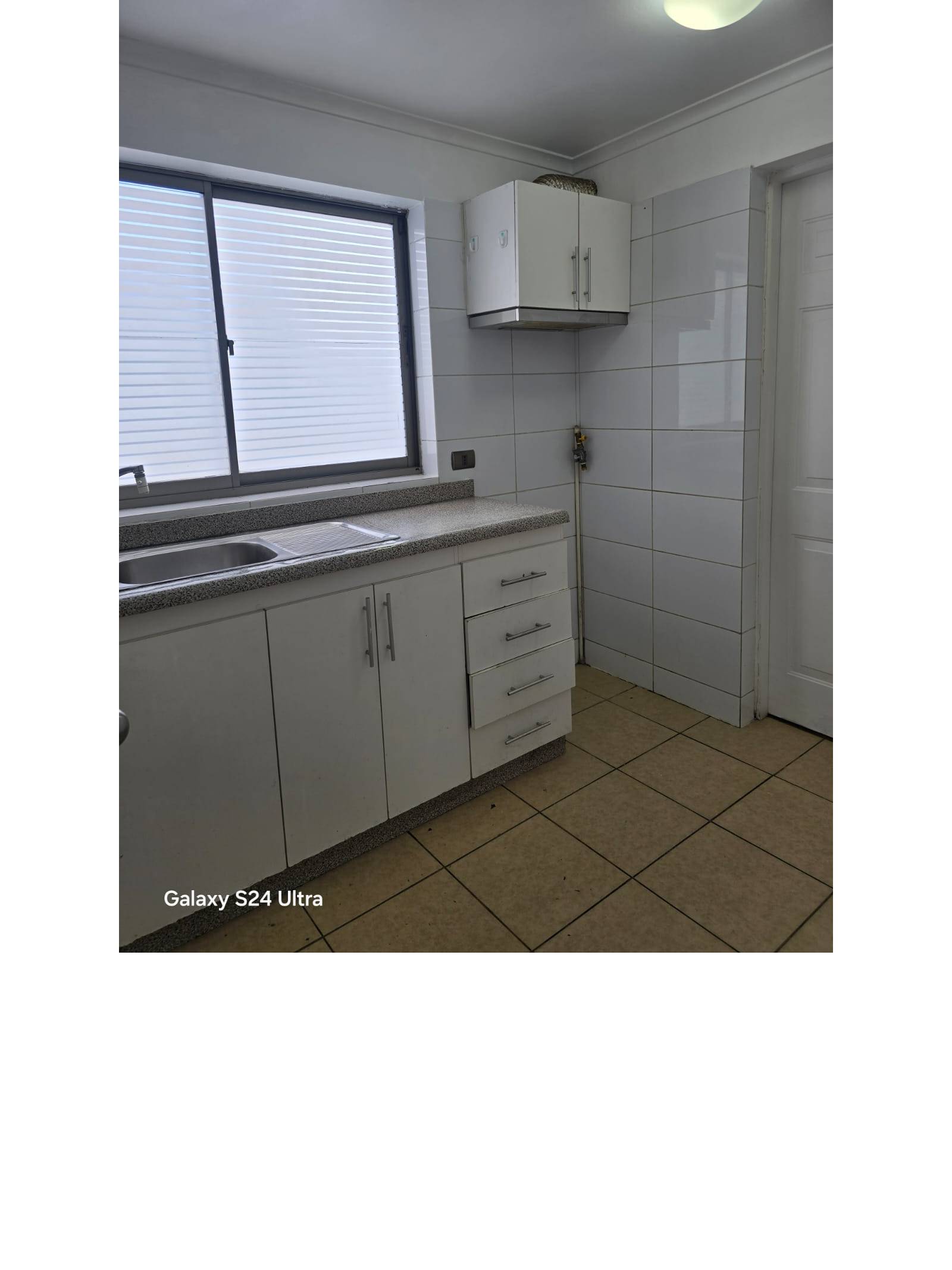 Mueble de cocina con lavaplatos y ventana con persiana