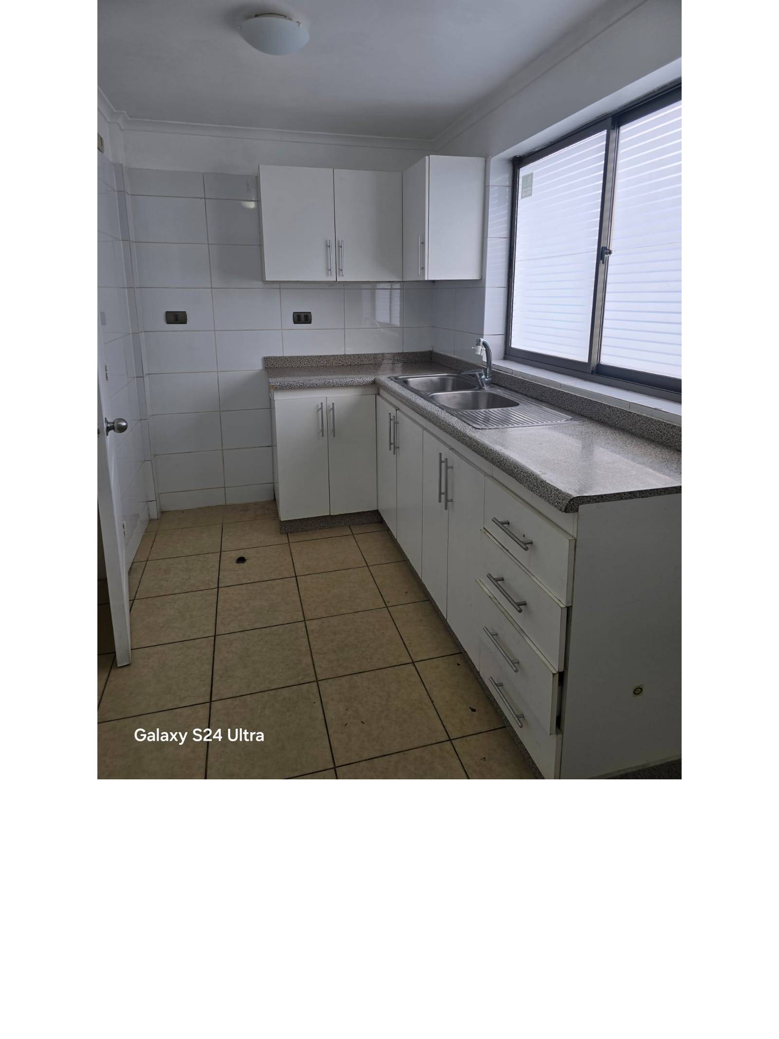 Cocina con muebles blancos, mesón y lavaplatos doble
