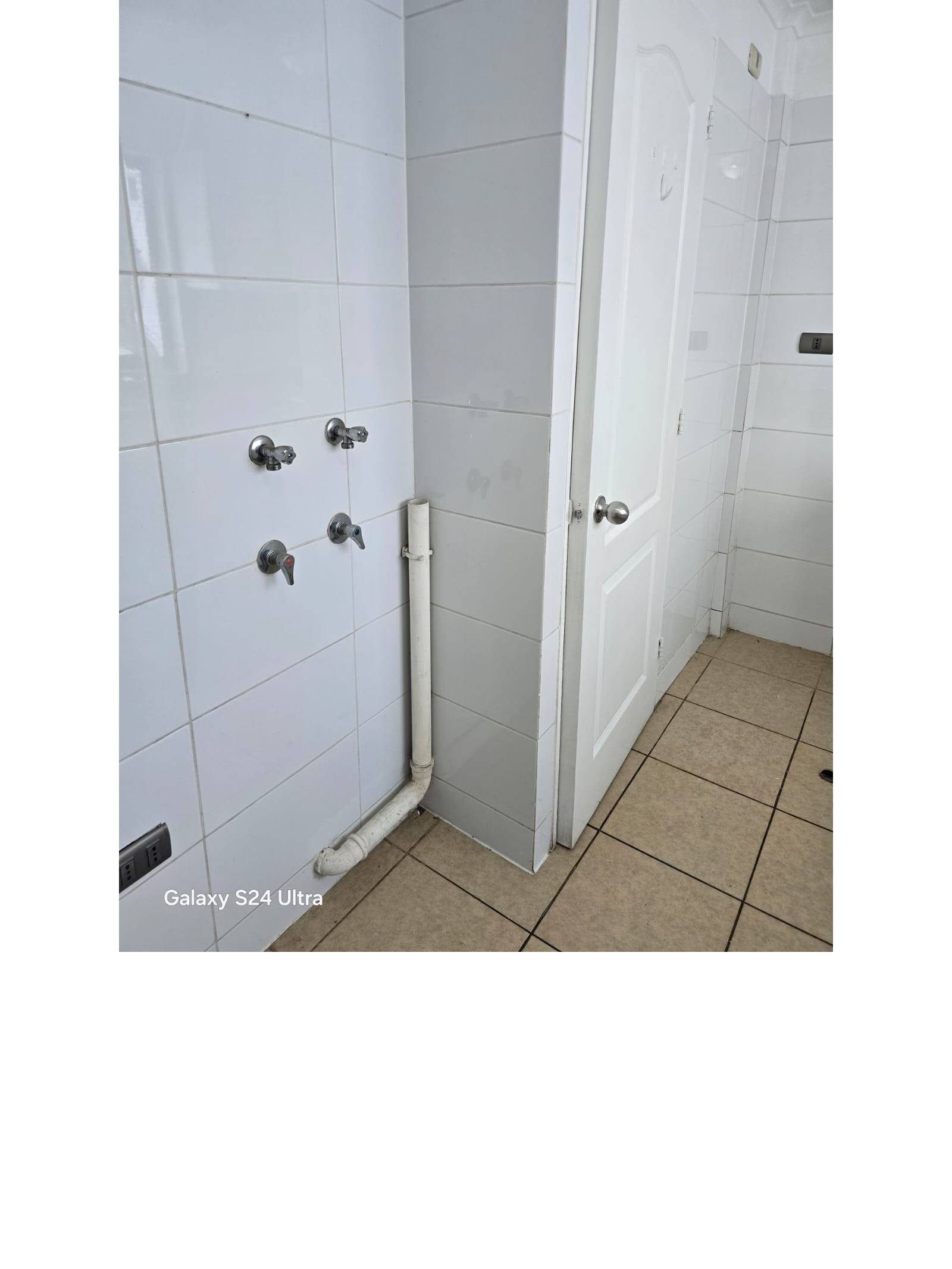 Conexiones para lavadora en pared de azulejos blancos