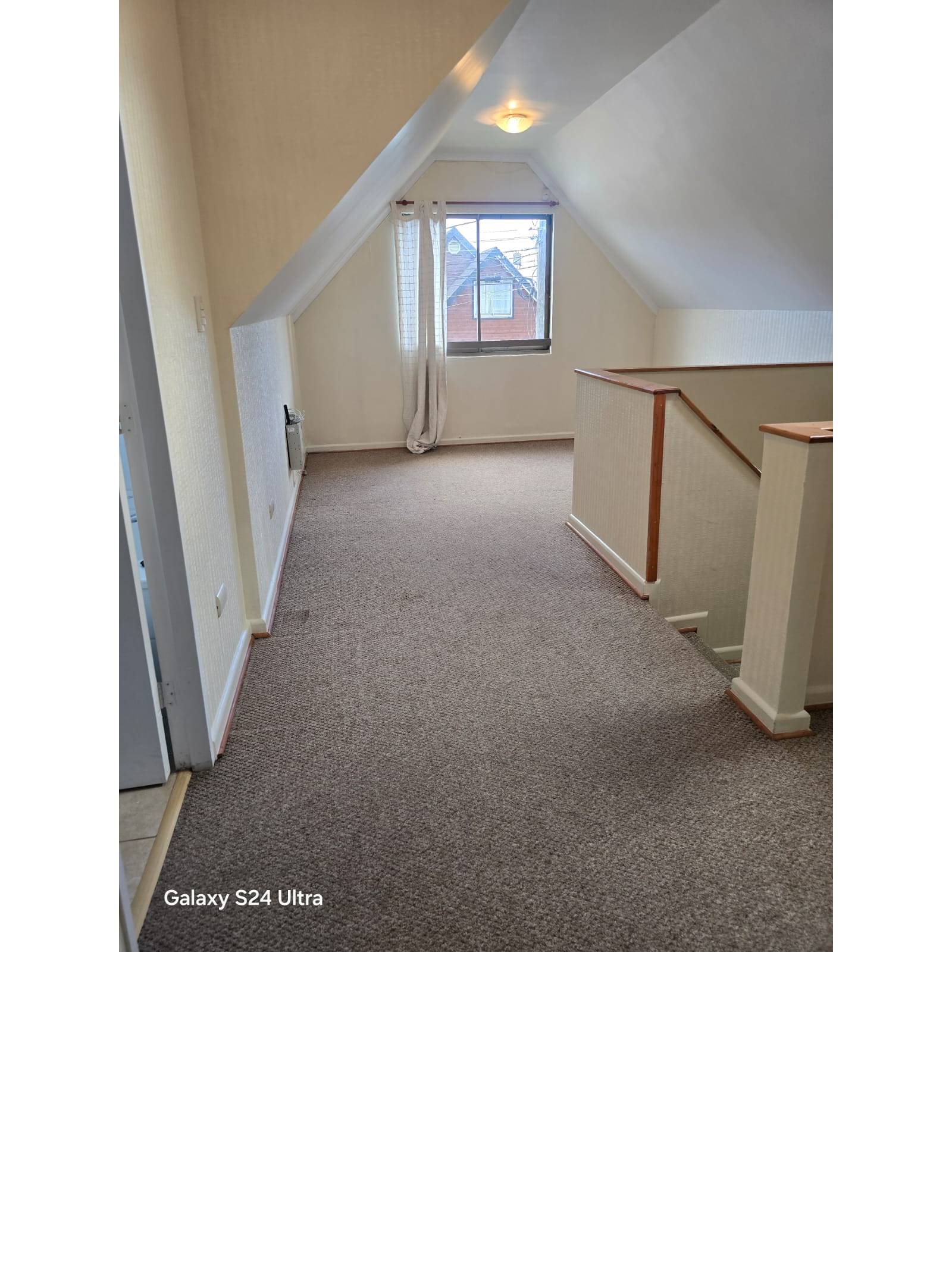 Planta alta alfombrada tipo mansarda con escalera y ventana