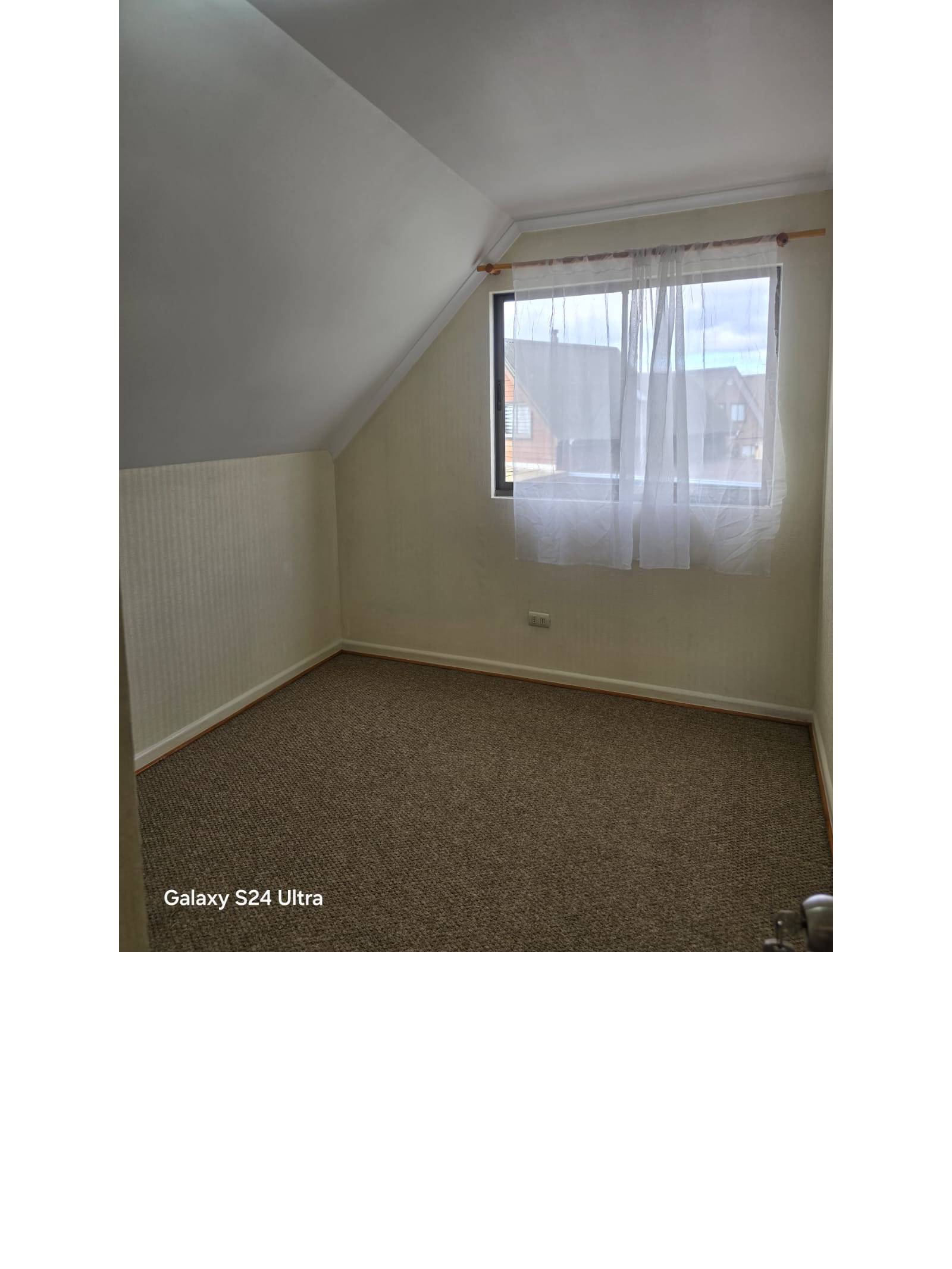 Dormitorio con cielo inclinado, alfombra y ventana al exterior