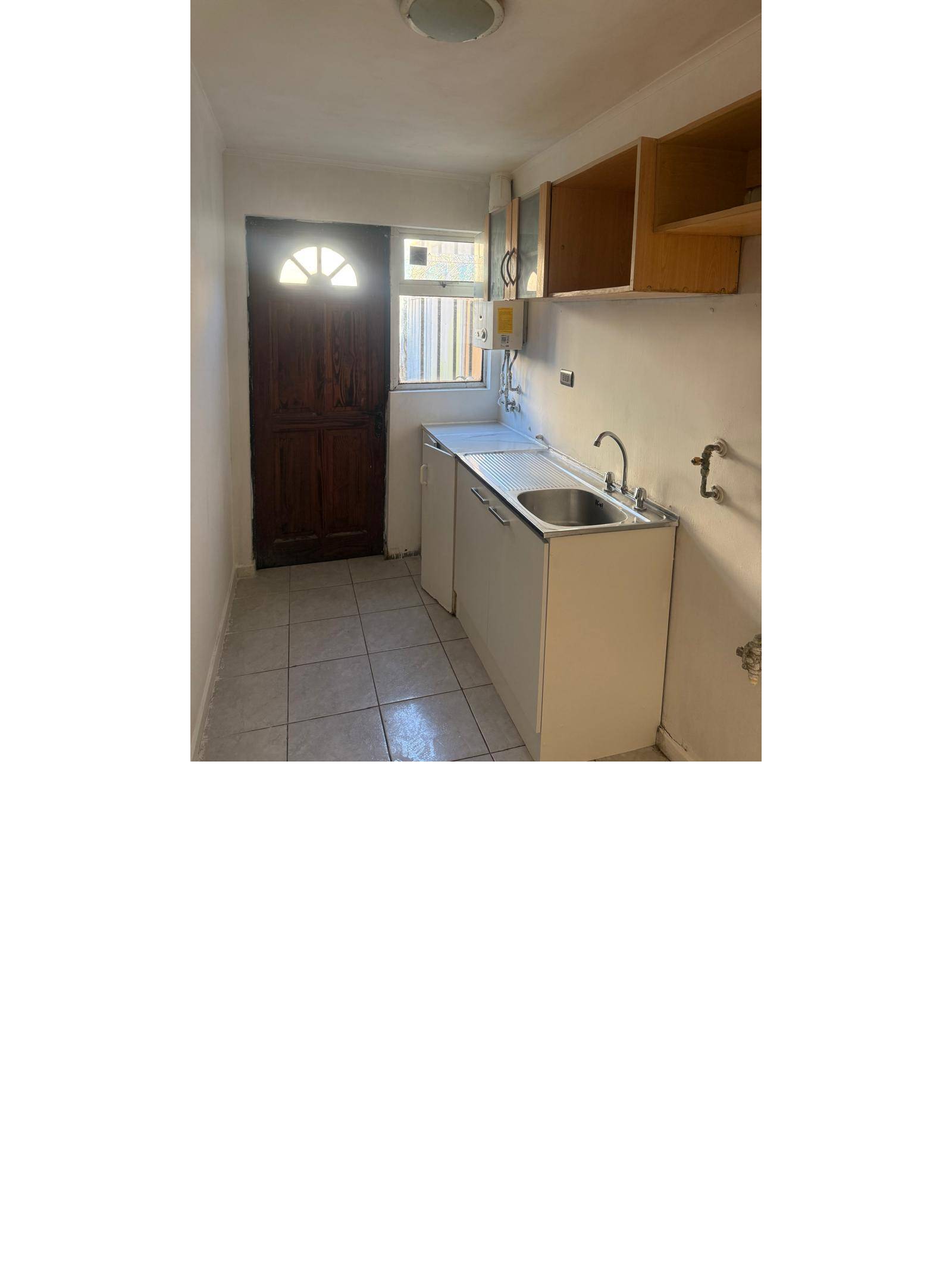 Mueble de cocina con lavaplatos y puerta de salida exterior.