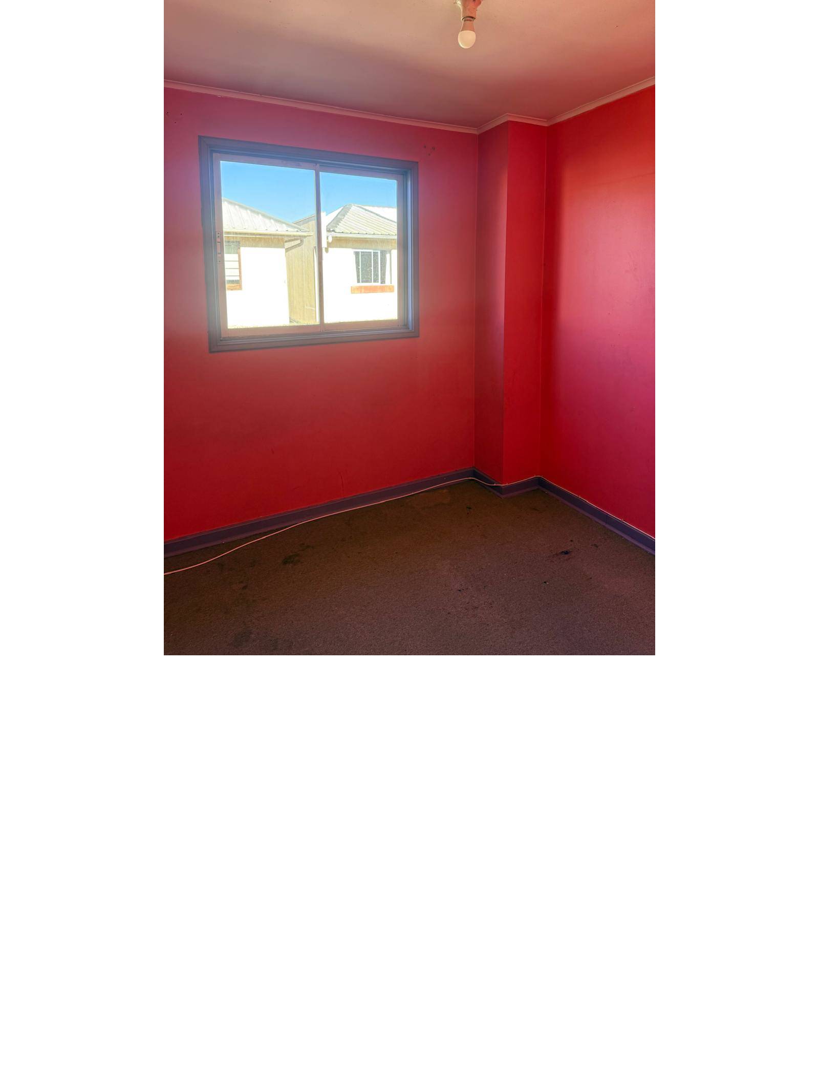 Dormitorio con paredes rojas y ventana al exterior.