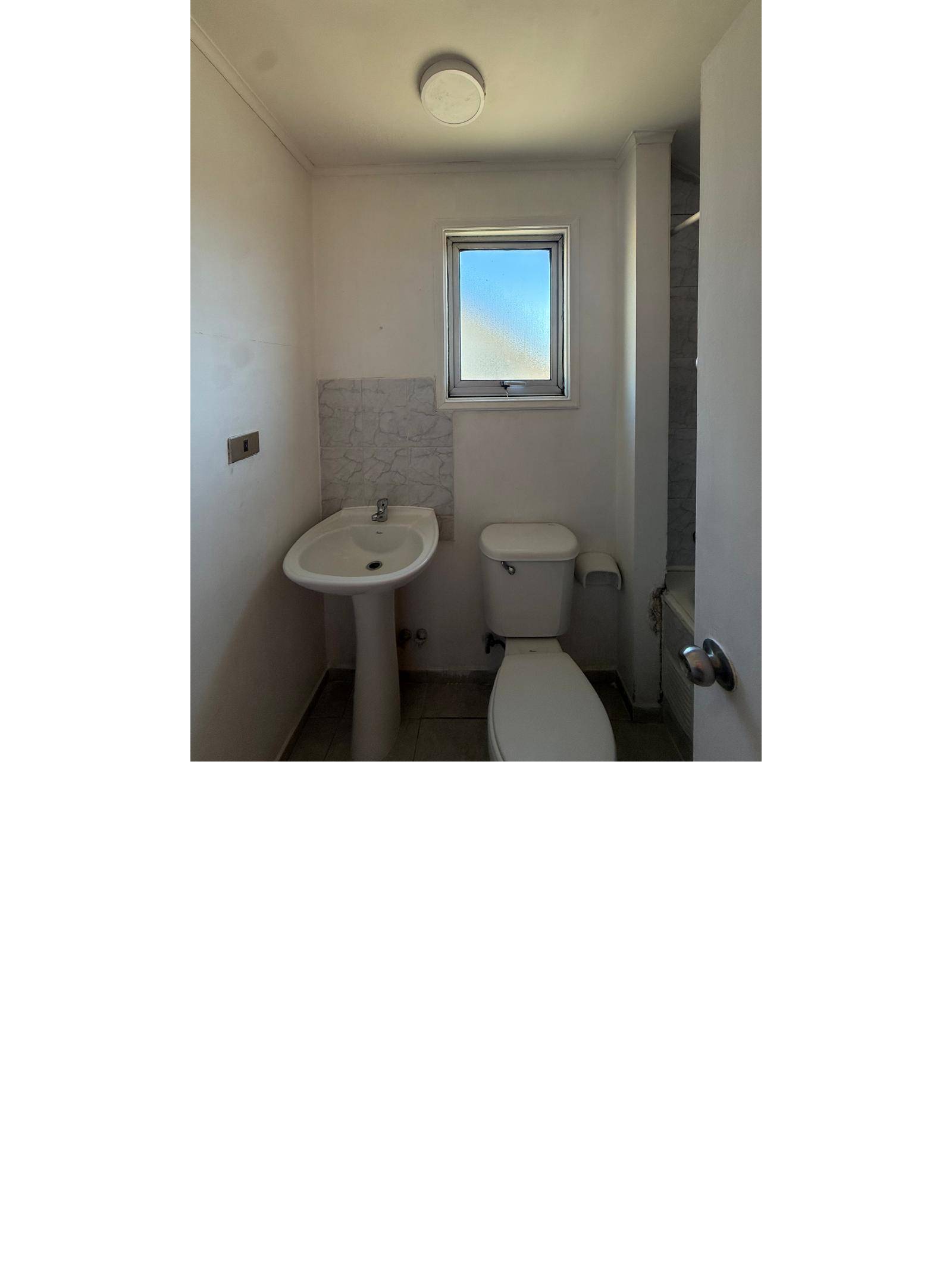 Baño con inodoro, lavamanos de pedestal y ventana.