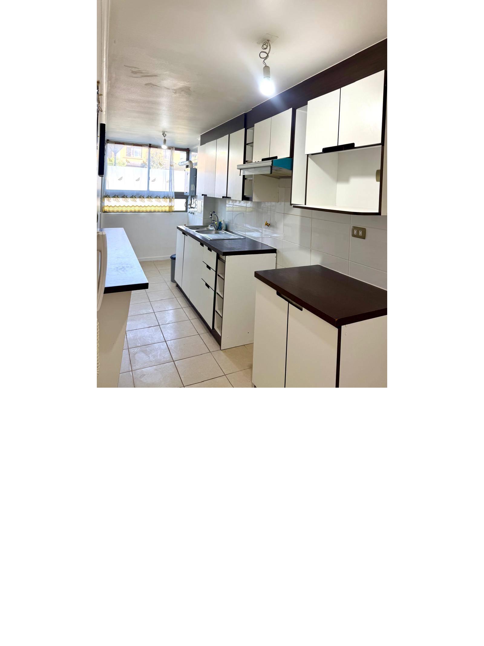 Cocina alargada con muebles blancos y cubierta oscura